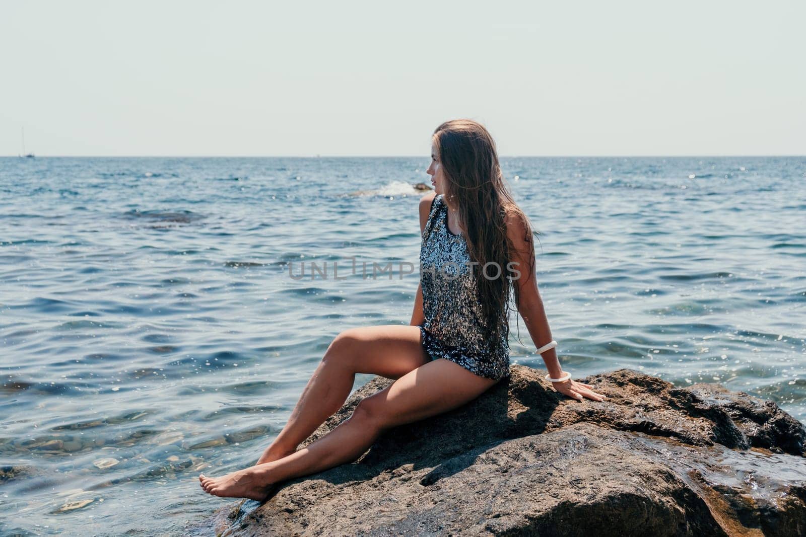 Woman travel sea. Young Happy woman in a long red dress posing on a beach near the sea on background of volcanic rocks, like in Iceland, sharing travel adventure journey