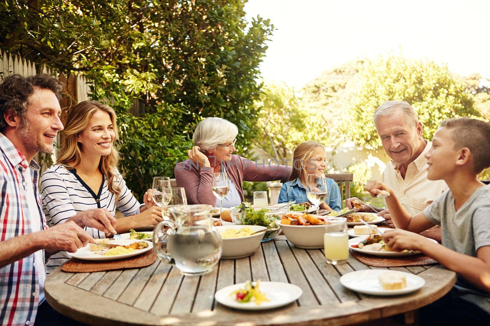 Family gatherings are the greatest. a family eating lunch together outdoors. by YuriArcurs