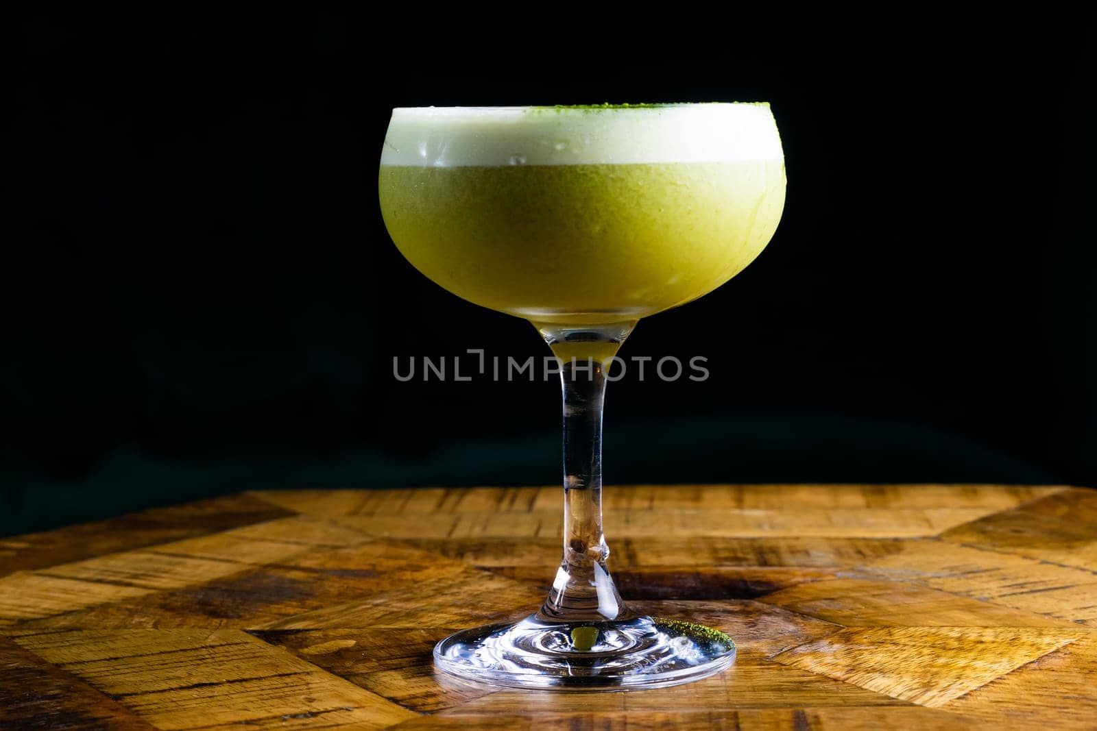 Stemmed cocktail glass with alcoholic drink, closeup isolated on black. Template design