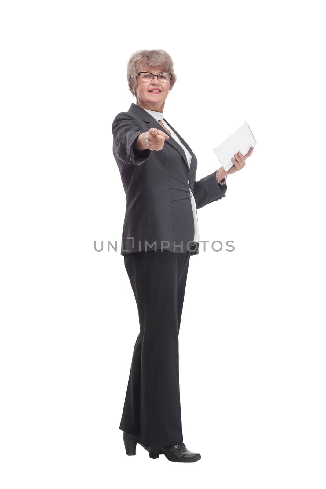 Happy mature woman pointing at camera with tablet pc on white background and smiling