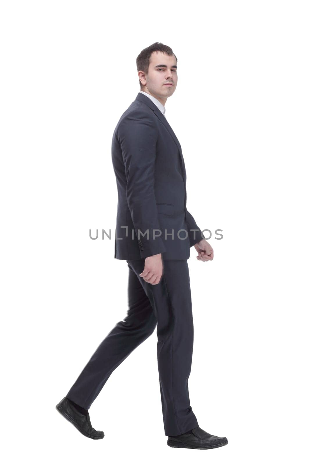picture of a young business man wearing black suit walking forward - side view