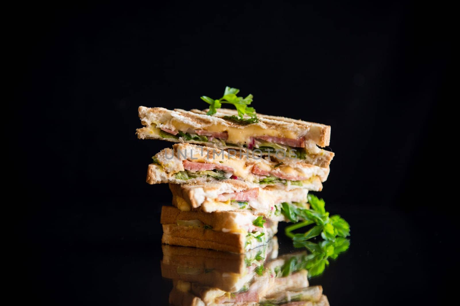 fried toasts stuffed with sausage, cheese and greens inside, isolated on black background.