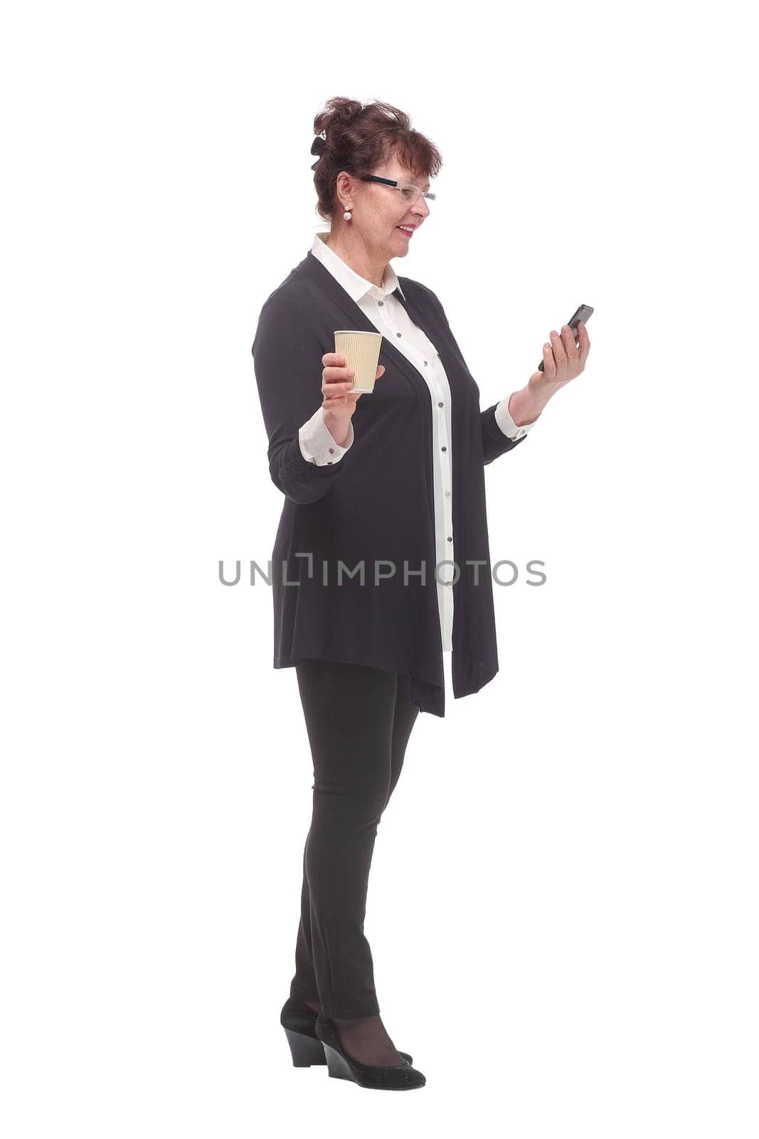 Portrait of thoughtful adult woman wearing eyeglasses holding cellphone and takeaway coffee cup isolated over white background in studio