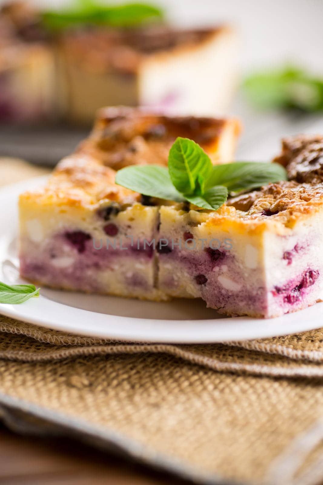 cooked cottage cheese casserole with berry filling in a plate on the table