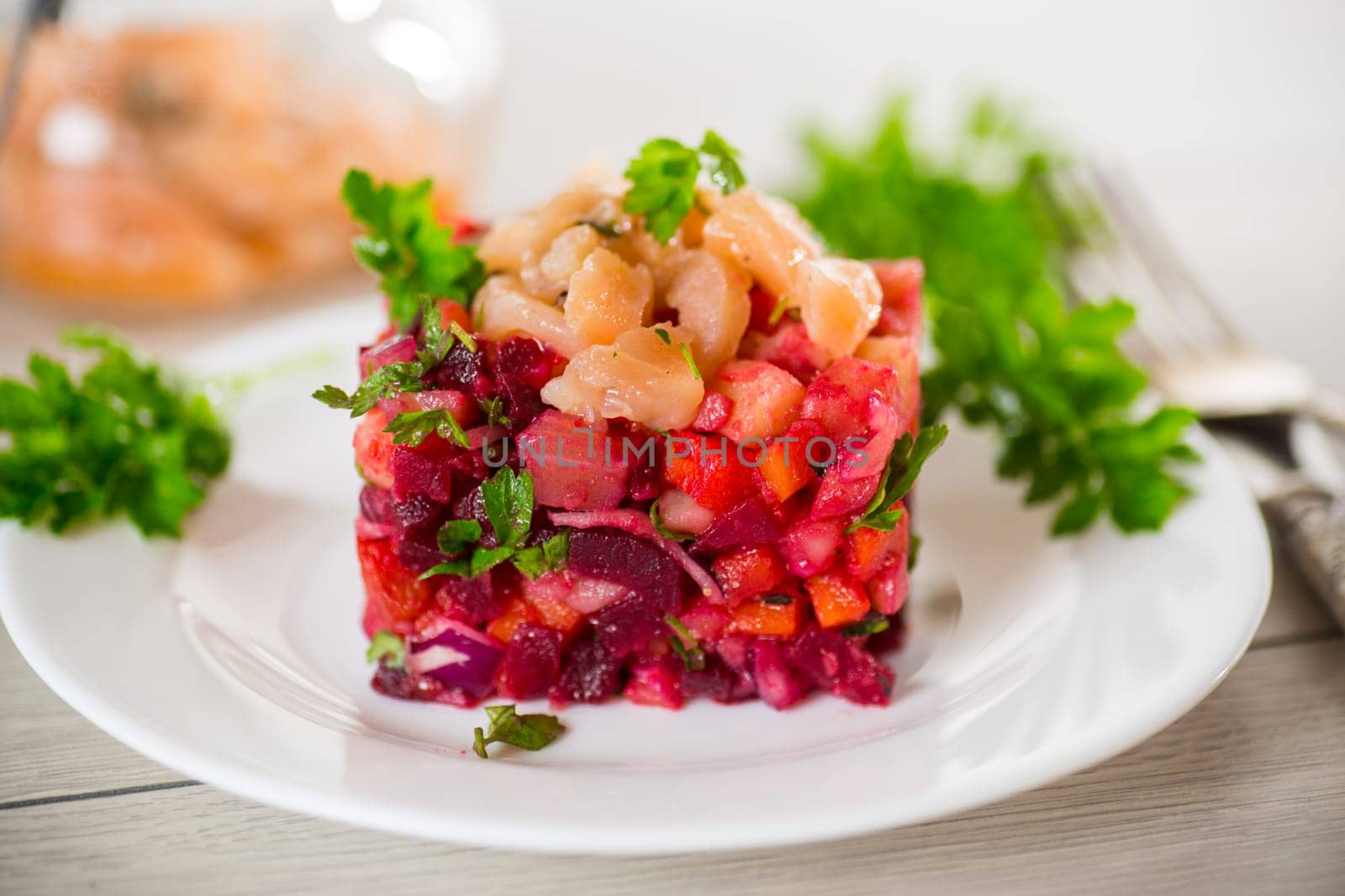 vinaigrette salad of boiled vegetables with salted fish in a plate, on a wooden table.