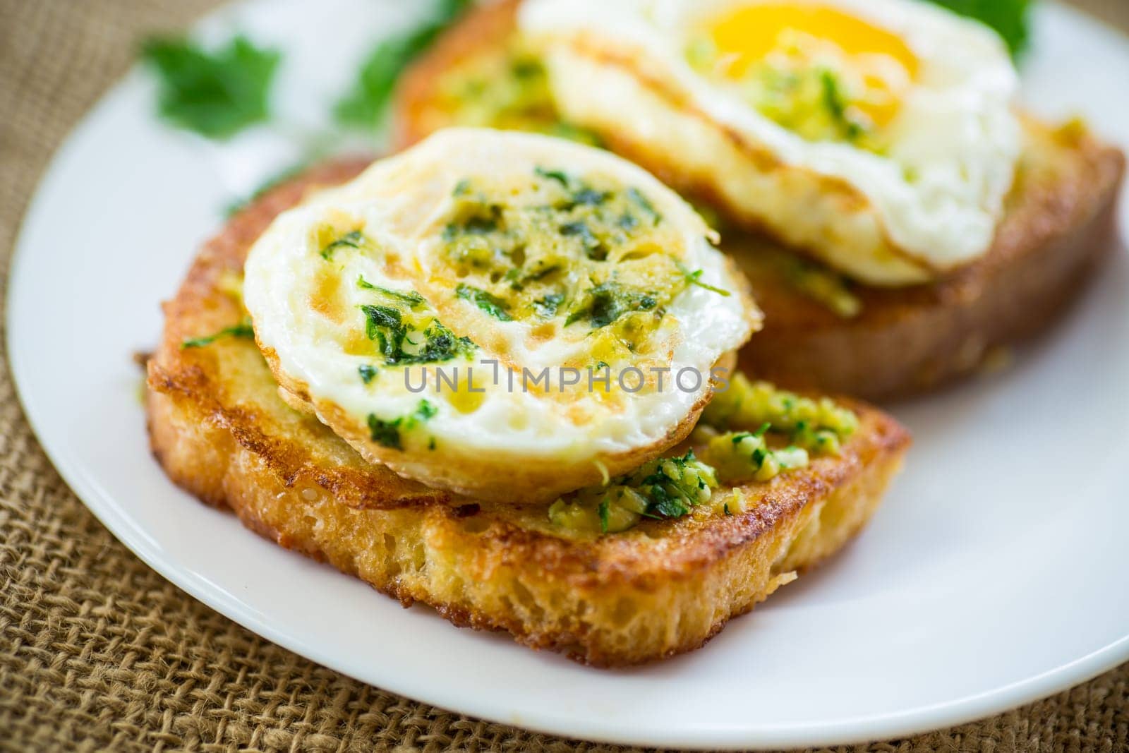 Fried croutons in batter with garlic and herbs and a fried egg in a plate, on a wooden table.