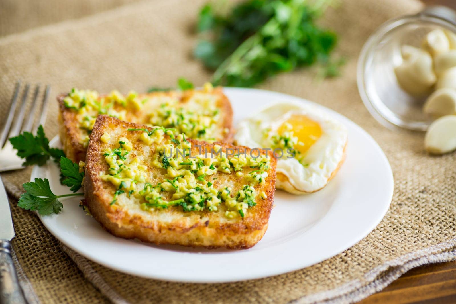 Fried croutons in batter with garlic and herbs in a plate, on a wooden table.