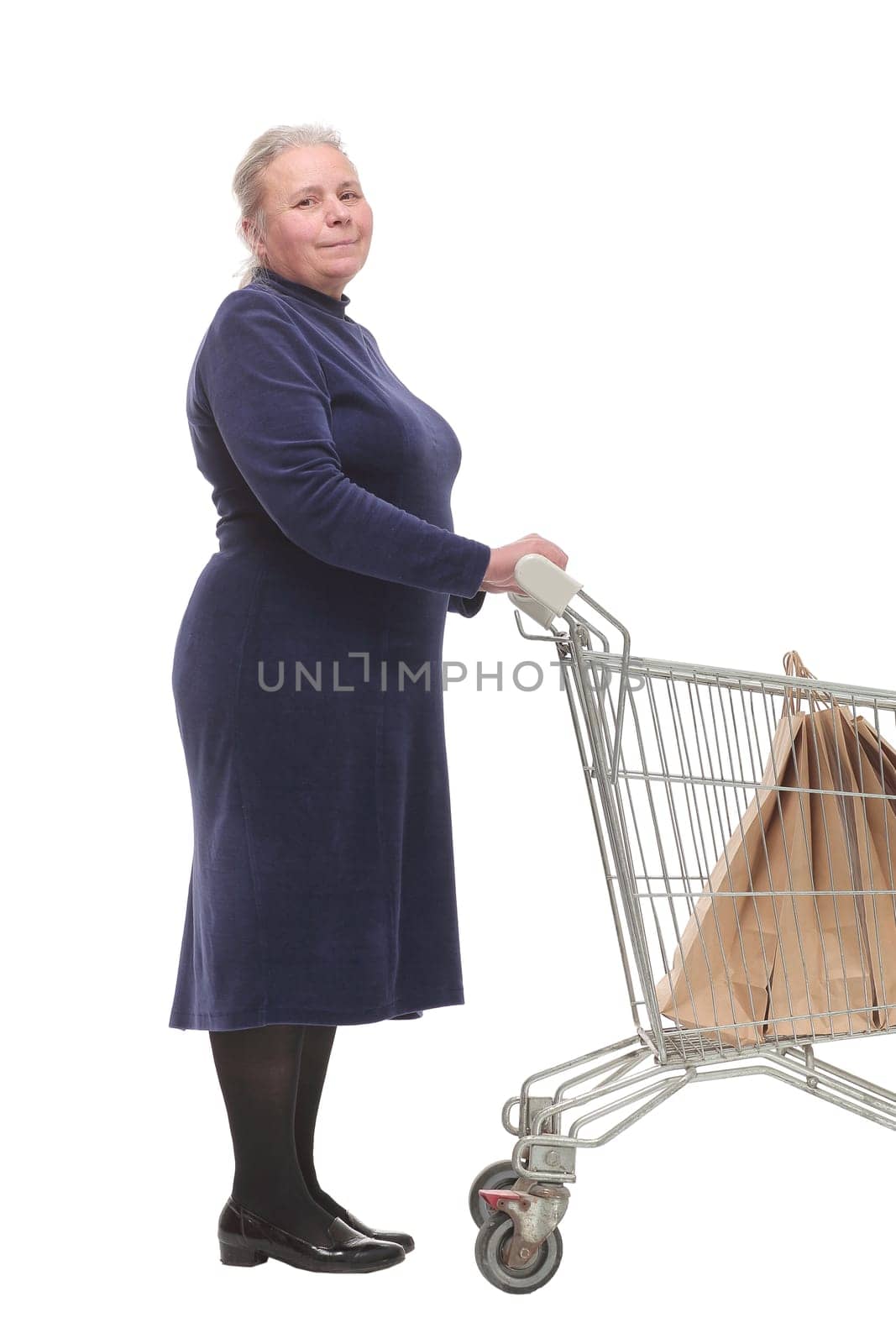 Profile of mature woman, pensioner shopping with shopping trolley looking at camera