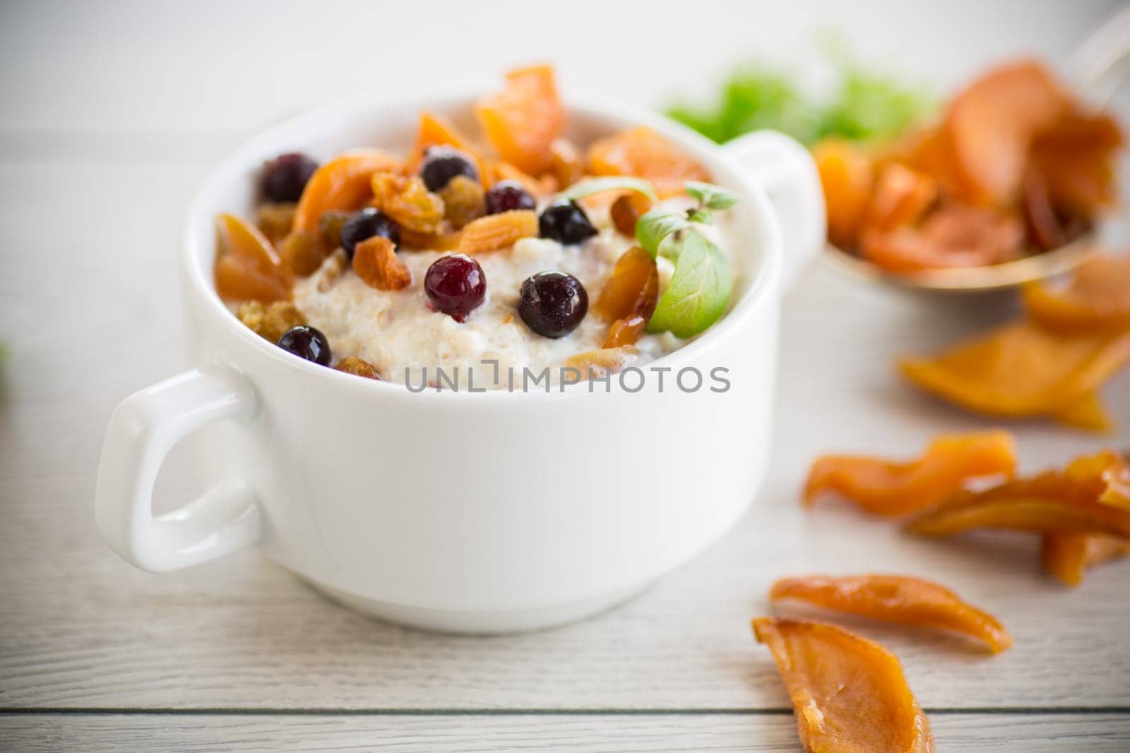 oatmeal with candied fruits, raisins in a plate on a wooden table.