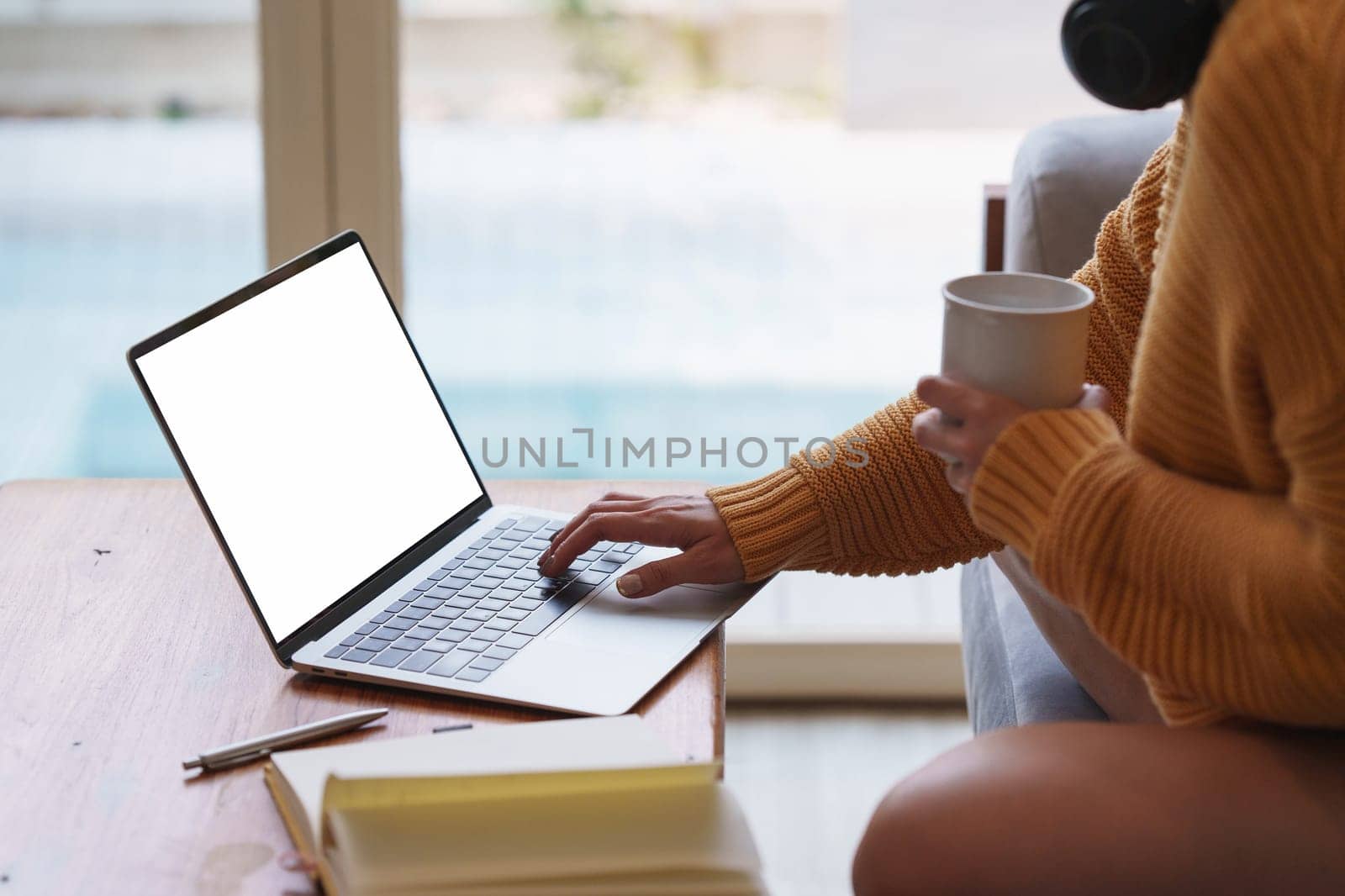 Online education, e-learning. Asian woman in stylish casual clothes, studying using a laptop, listening to online lecture, taking notes, online study at home.