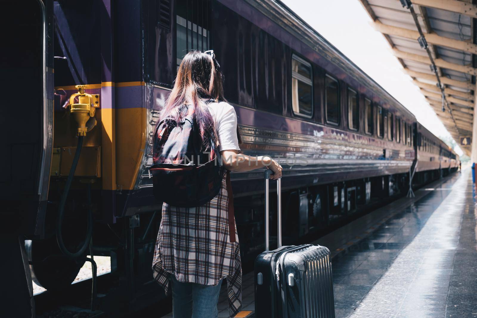 Image of a woman with a rucksack standing at a train station waiting to board a train. concept of solo travel by itchaznong