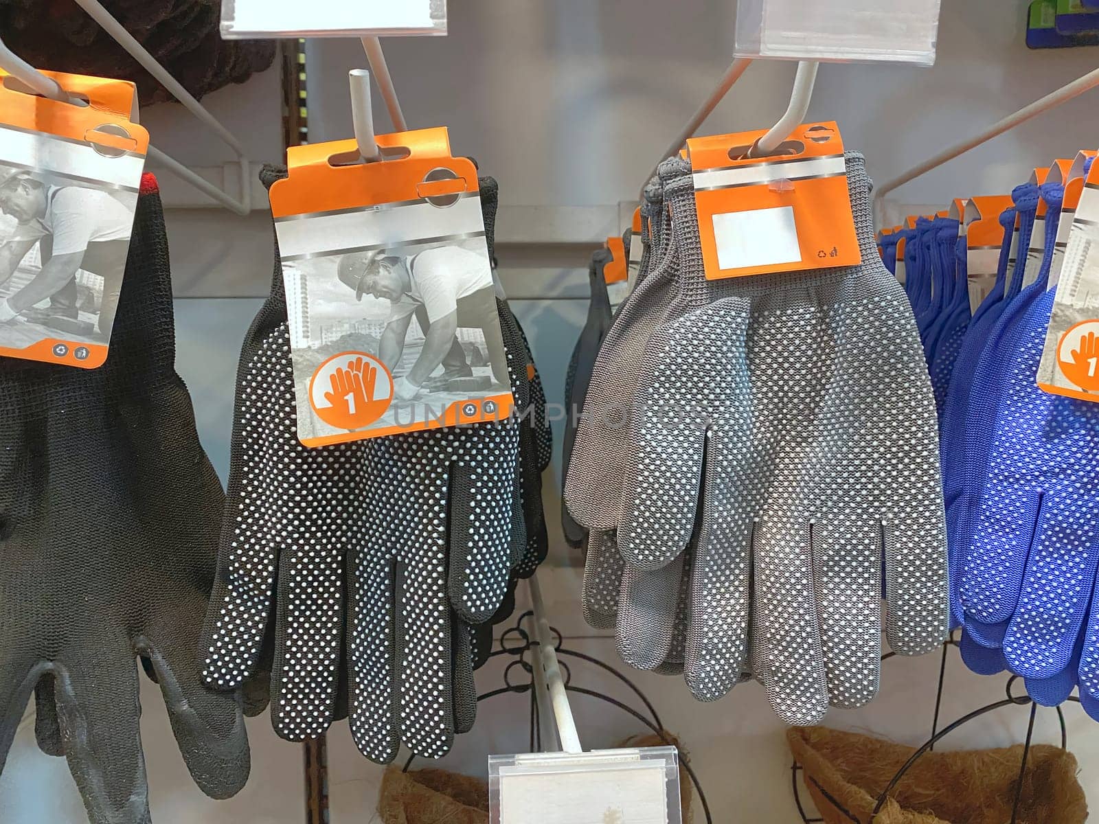 black and grey gloves hanging on shelf in hardwareshop
