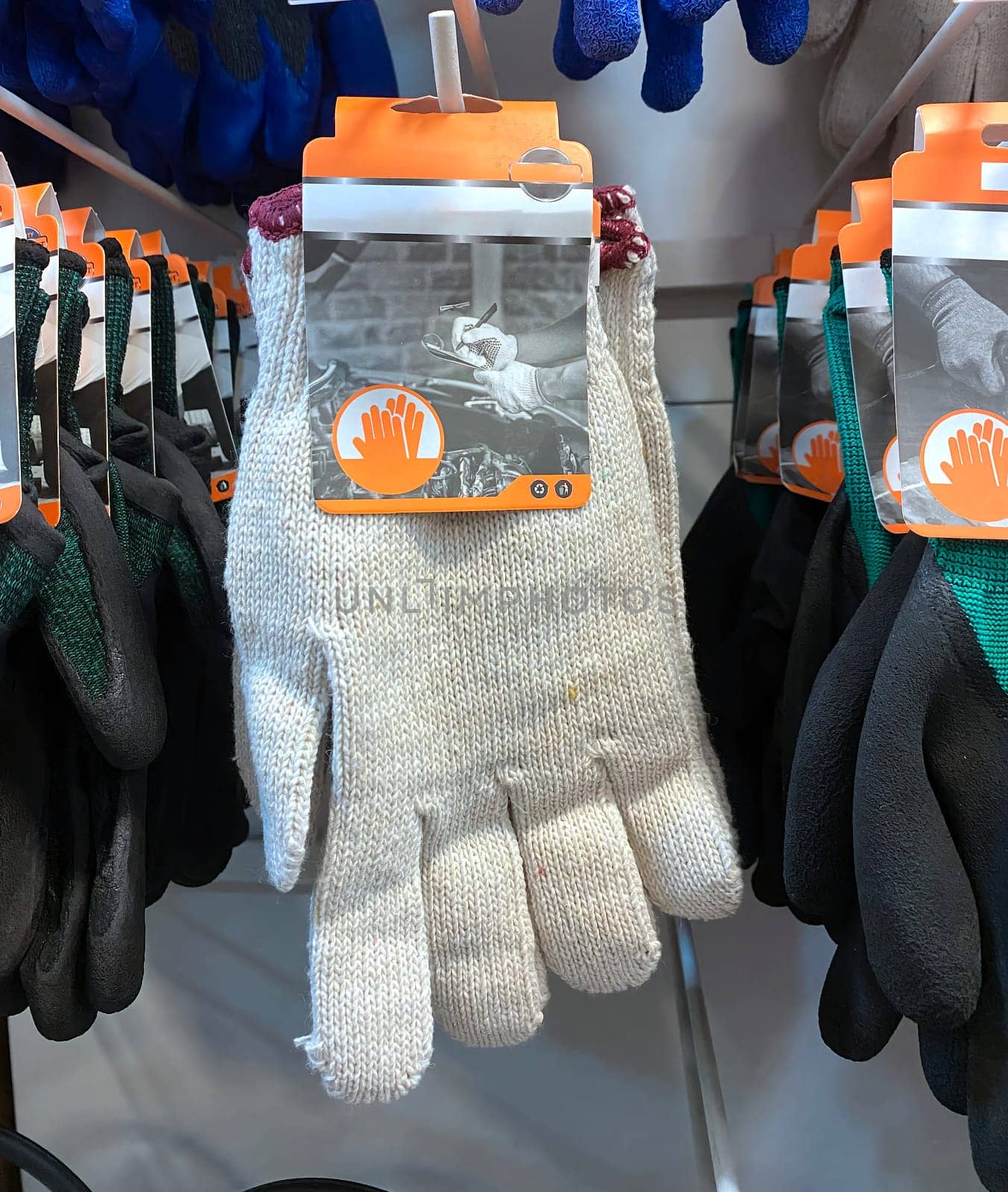 white cloth gloves hanging on shelf in hardware shop. fabric gloves for working, gloves for prevent slip on working. by capple