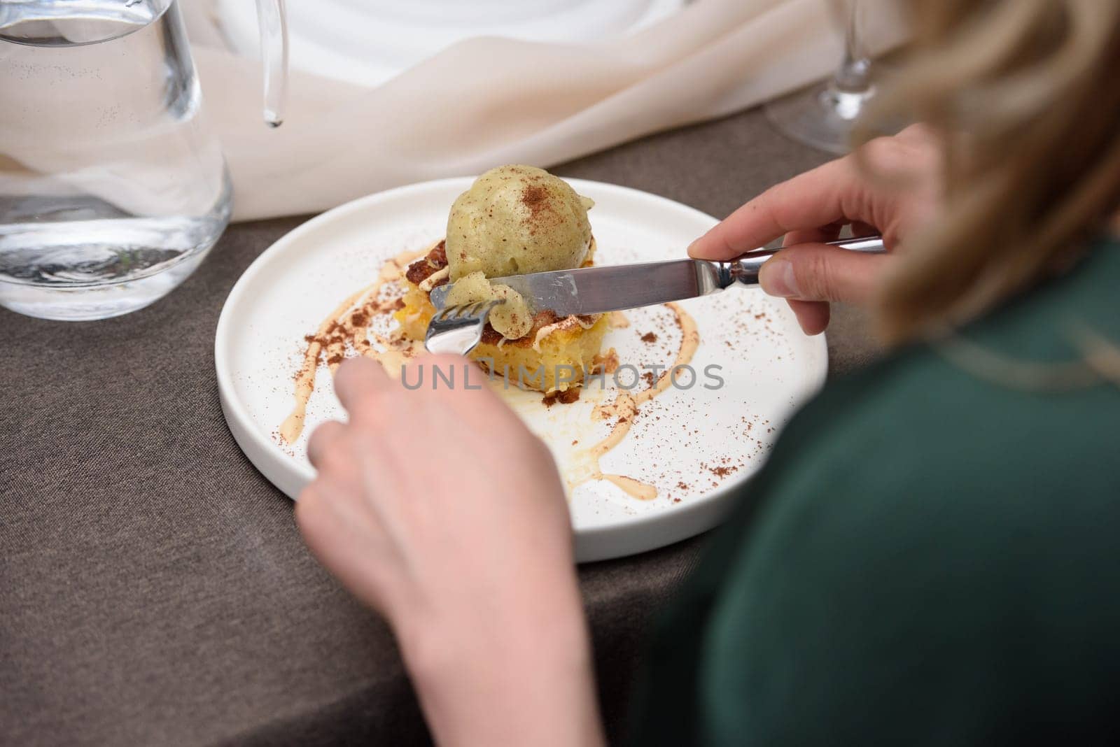 Woman eats portokalopita, greek orange cake made with shredded filo, greek yoghurt, and olive oil with vanilla ice cream. Mediterranean cuisine dessert.