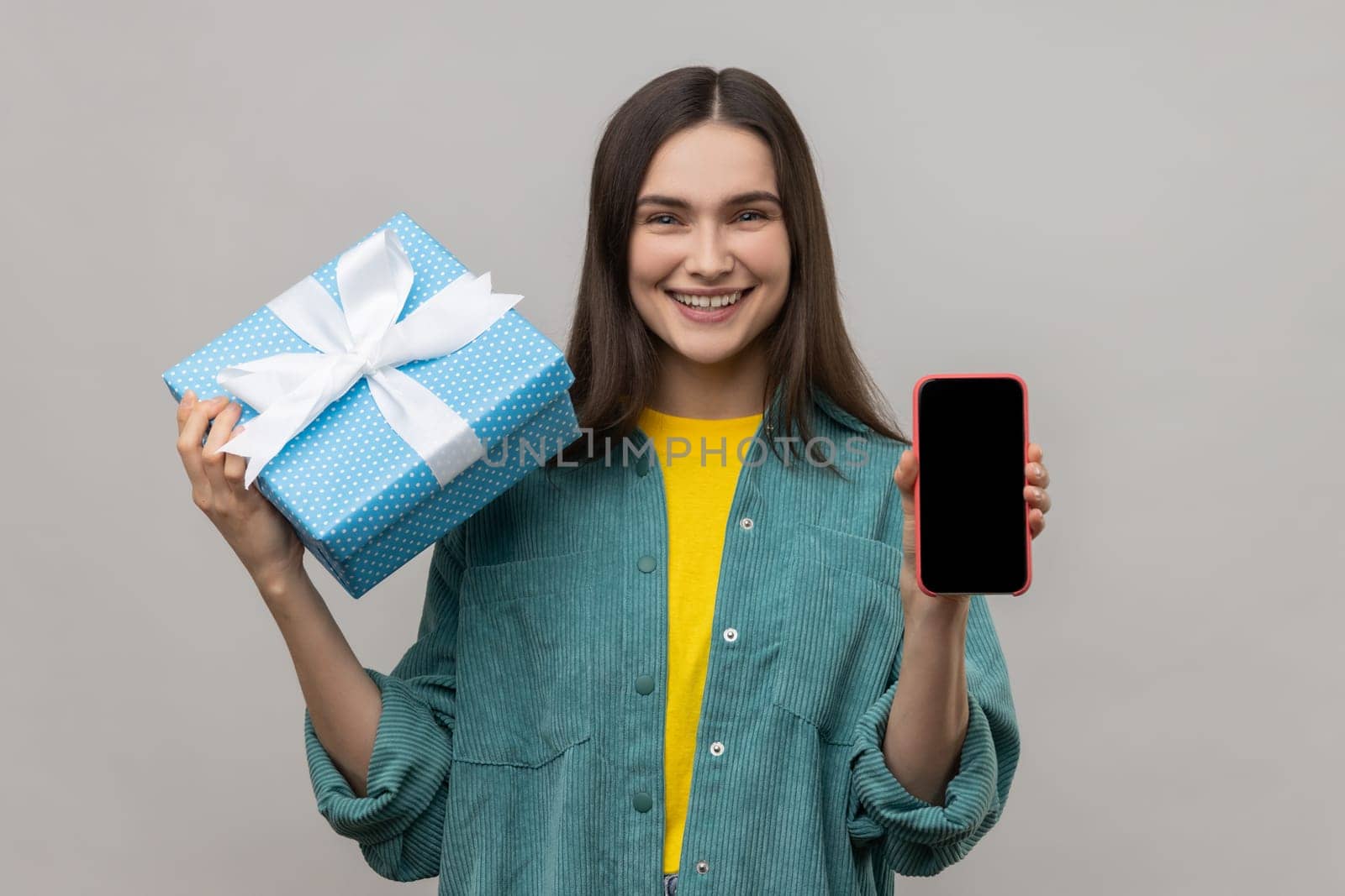 Woman holding gift box and cell phone with empty display for online shopping advertising. by Khosro1