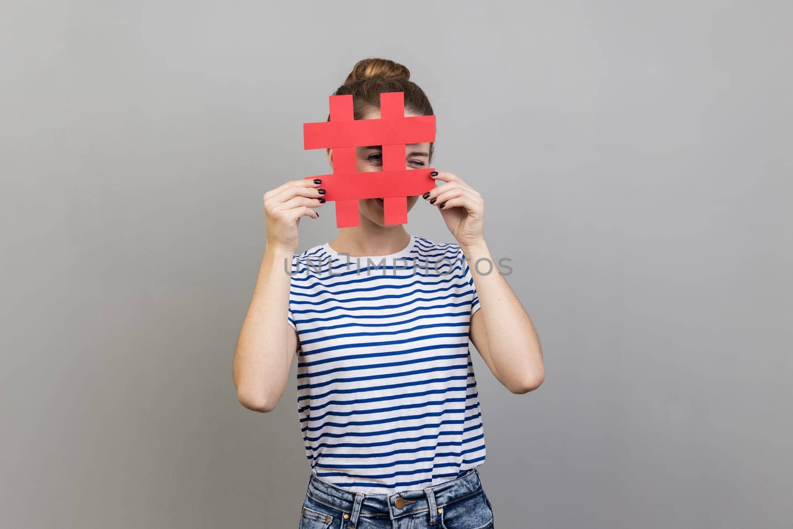 Woman looking through red hashtag sign, looking for proper posts in social media, spying. by Khosro1