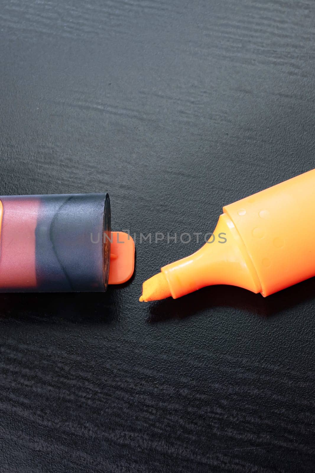 Orange marker on a black wooden table close up
