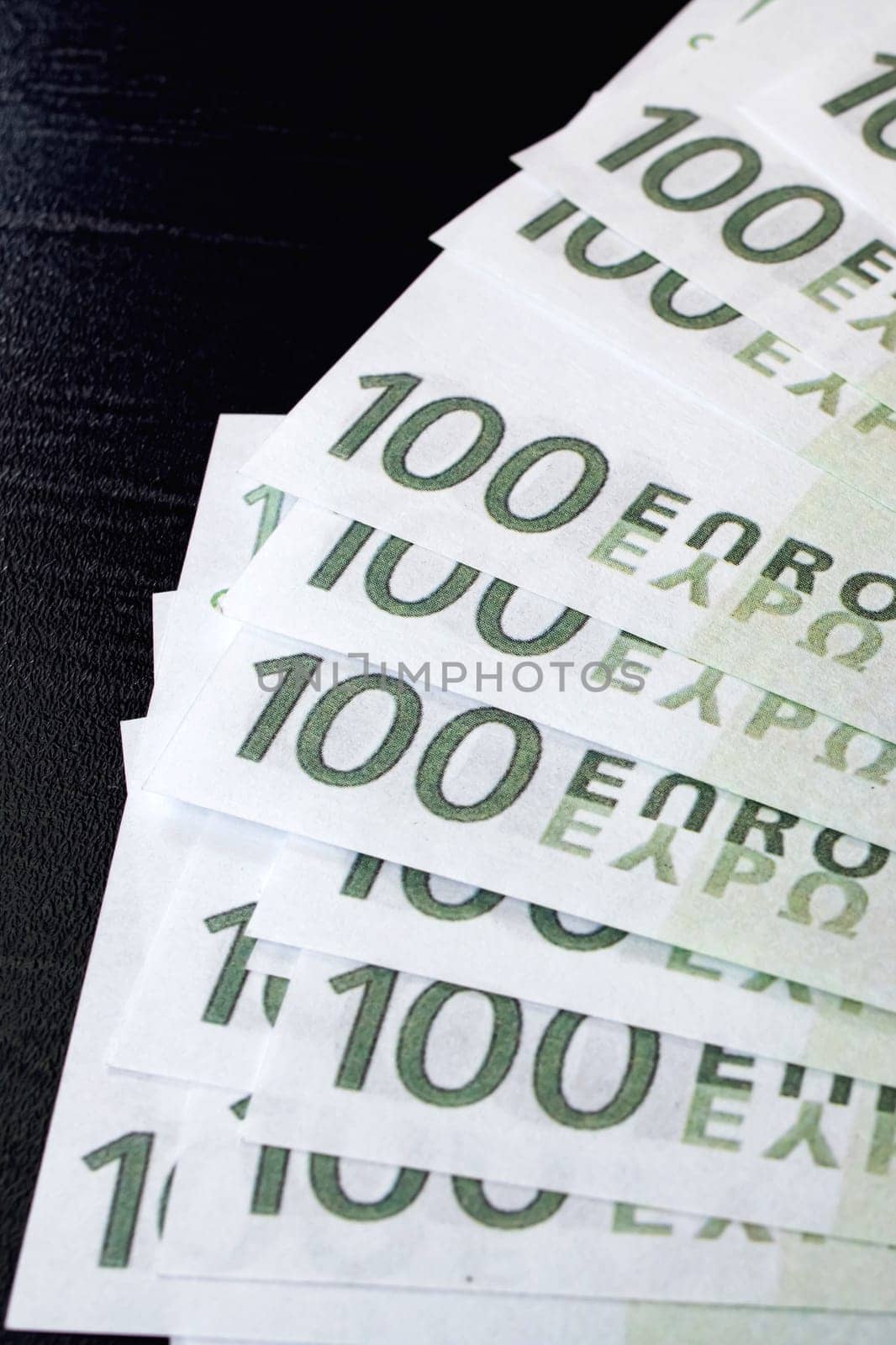Fanned out bills of one hundred euros on black background