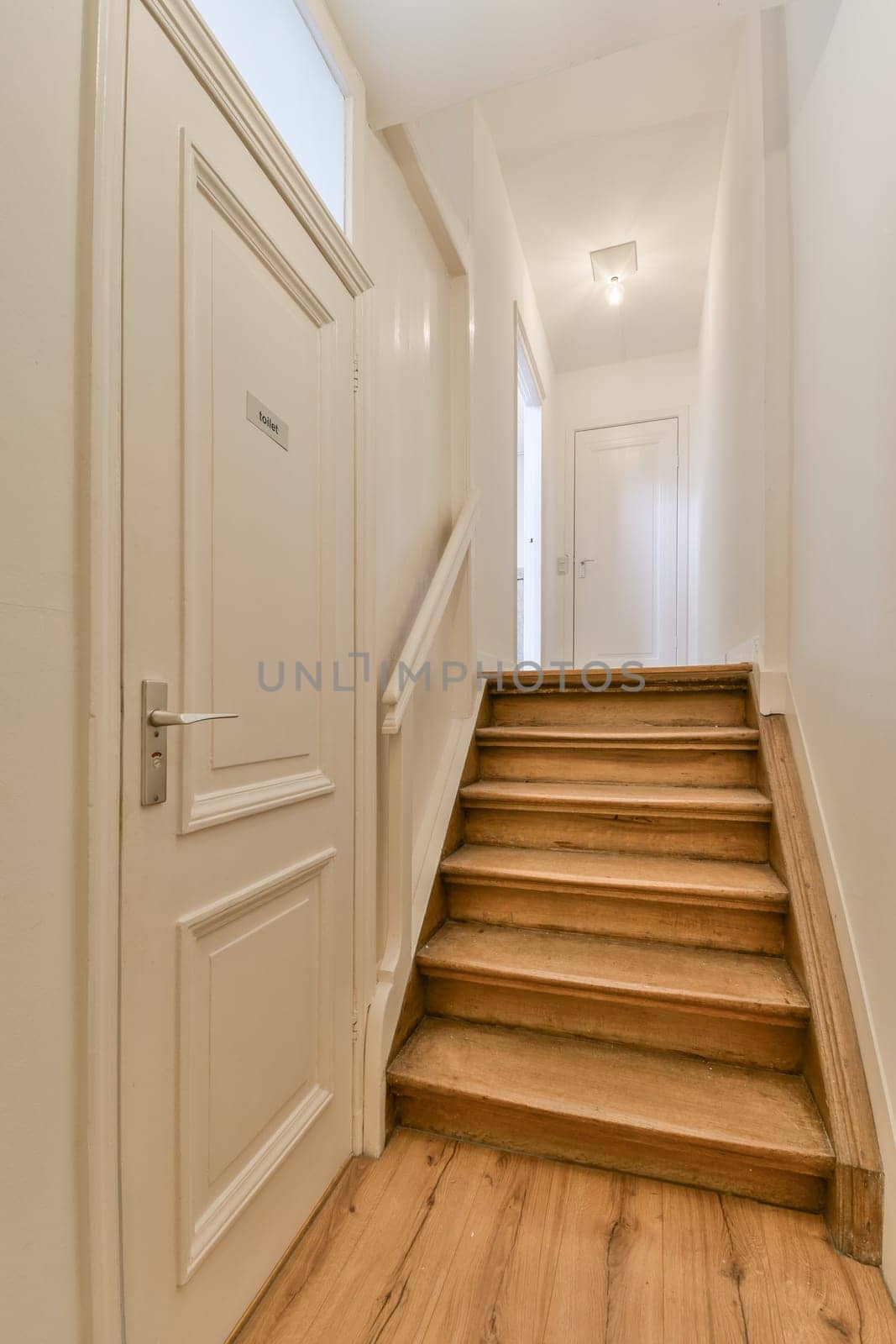 an empty hallway with wooden floors and white door leading to the second floor in a house or condo apartment building