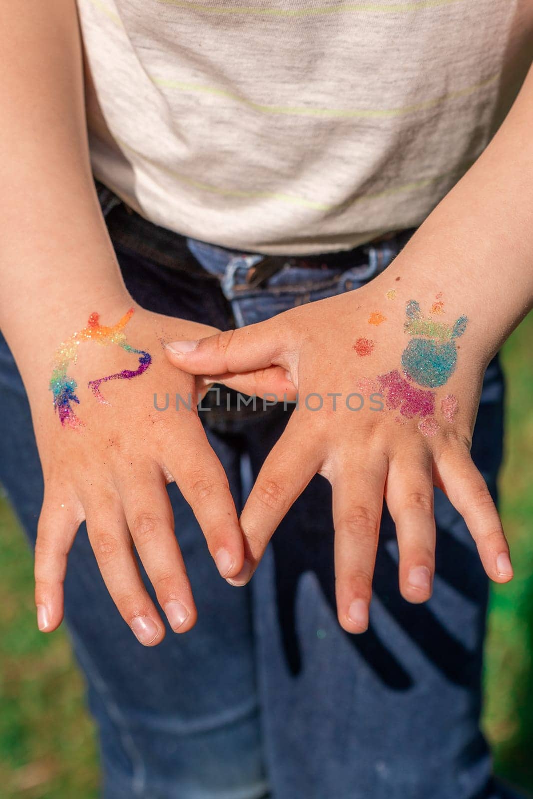 Shimmering sparkling glitter tattoo on a child's hand at a birthday party. Body art