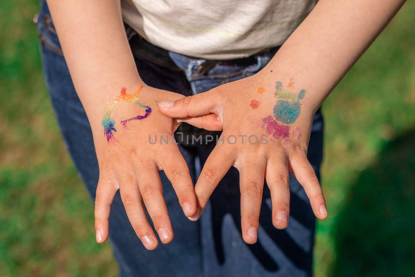 Shimmering sparkling glitter tattoo on a child's hand at a birthday party. Body art