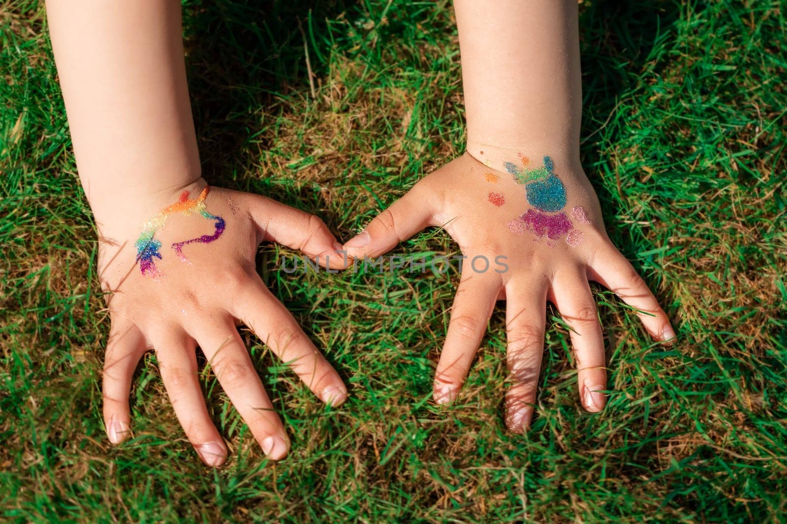 Shimmering sparkling glitter tattoo on a child's hand at a birthday party. Body art