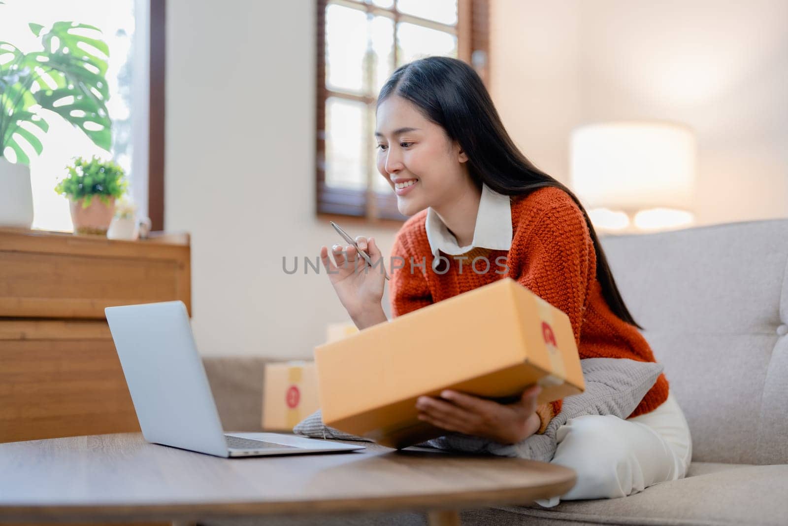 Starting small business entrepreneur of independent young Asian woman online seller is using computer and taking orders to pack products for delivery to customers. SME delivery concept.