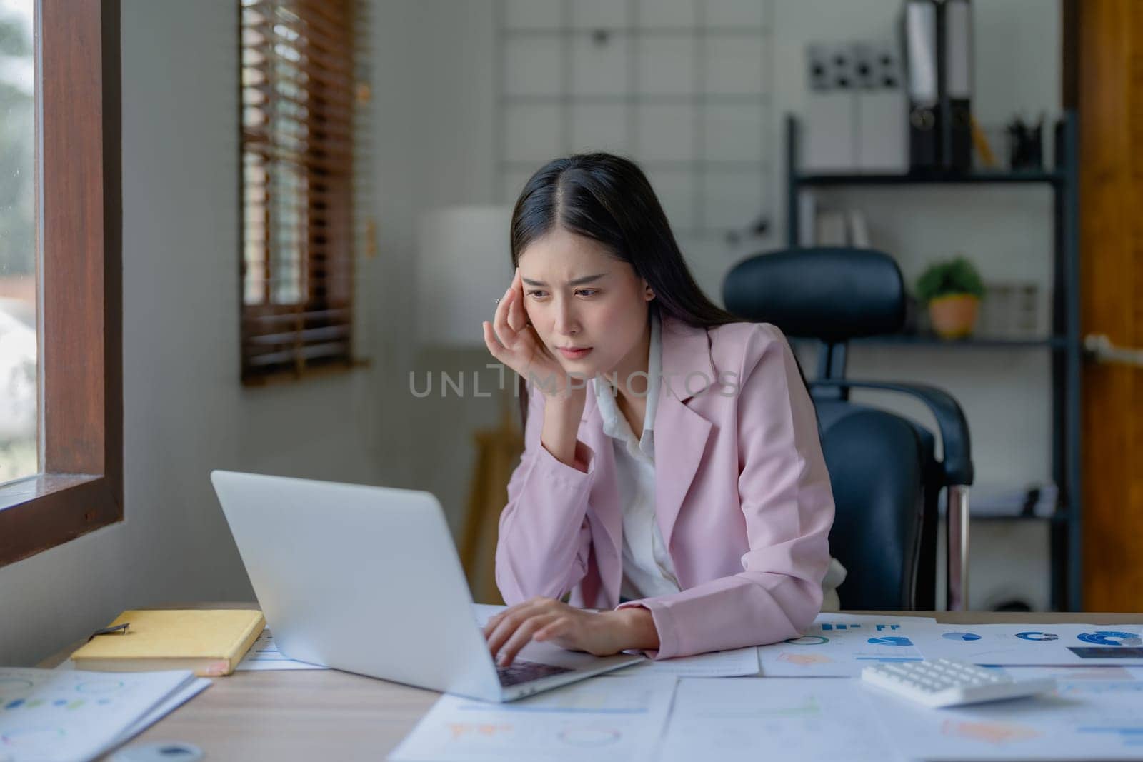 Portrait of business owner, woman using computer and financial statements Anxious expression on expanding the market to increase the ability to invest in business.