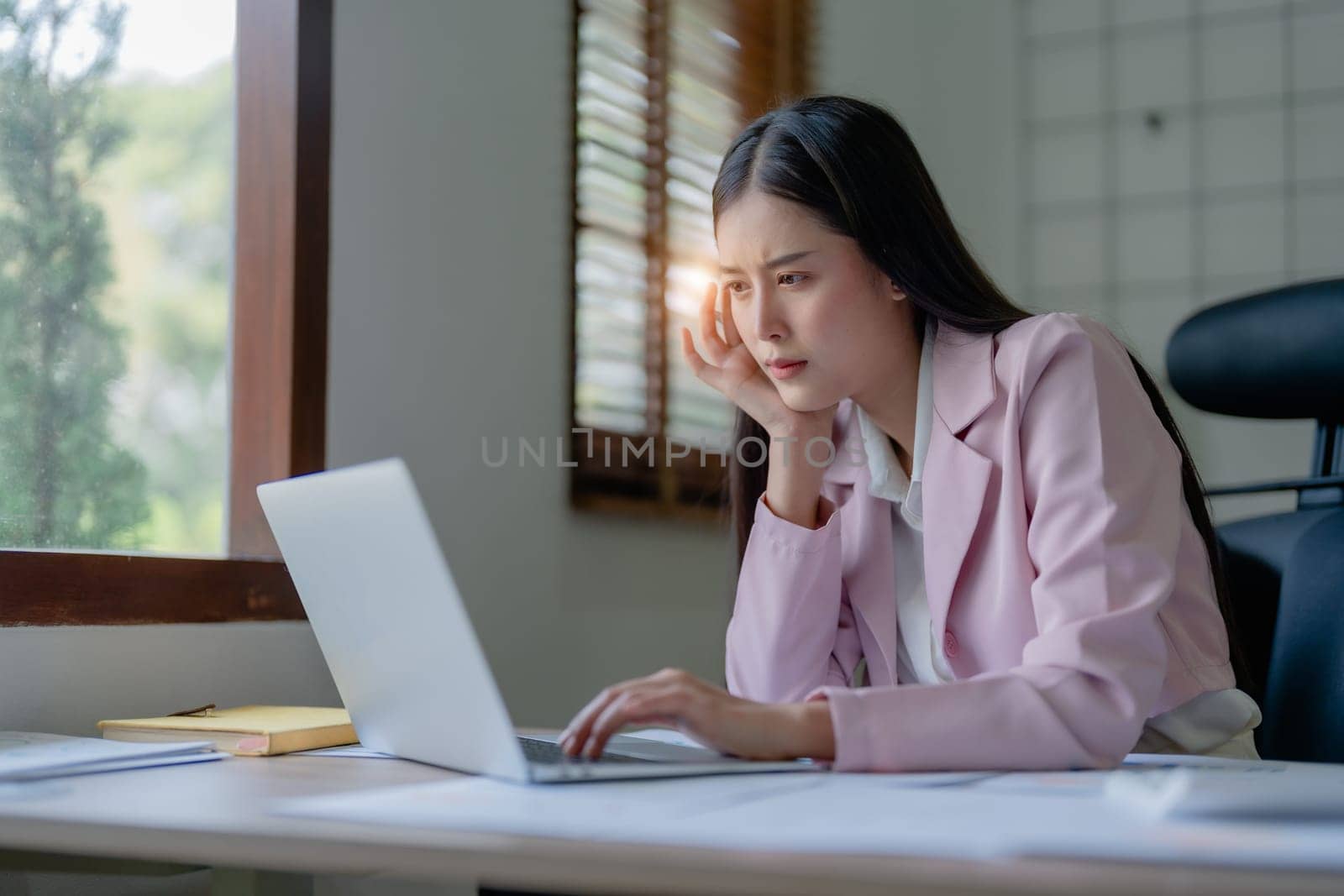 Portrait of business owner, woman using computer and financial statements Anxious expression on expanding the market to increase the ability to invest in business.