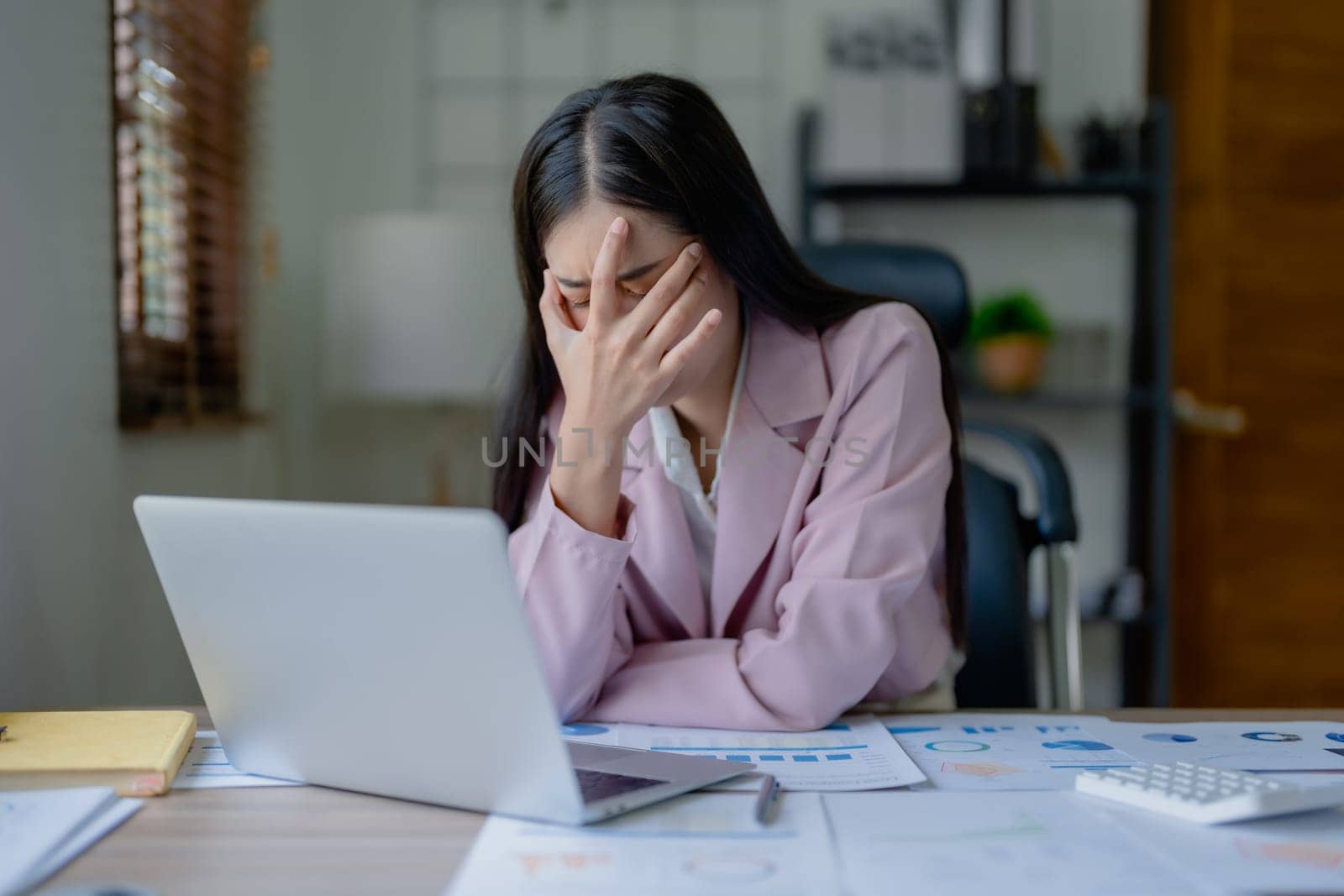 Portrait of a young Asian woman showing acute headache from sitting for a long time at work