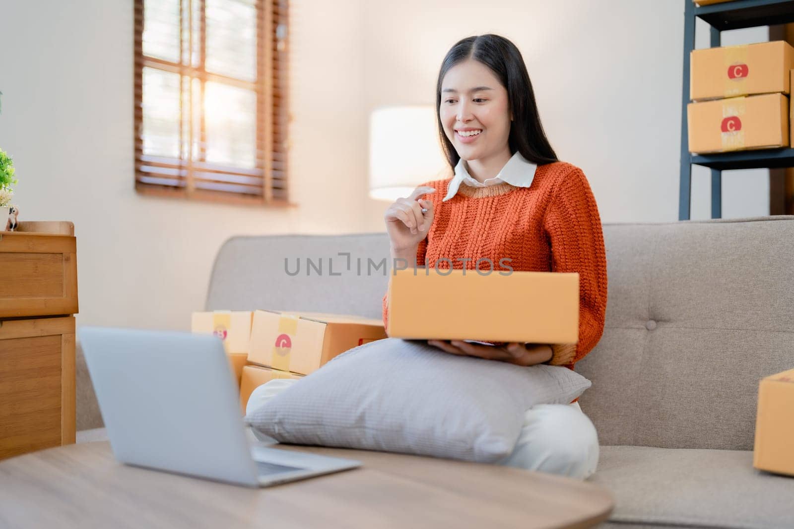 Starting small business entrepreneur of independent young Asian woman online seller is using computer and taking orders to pack products for delivery to customers. SME delivery concept.