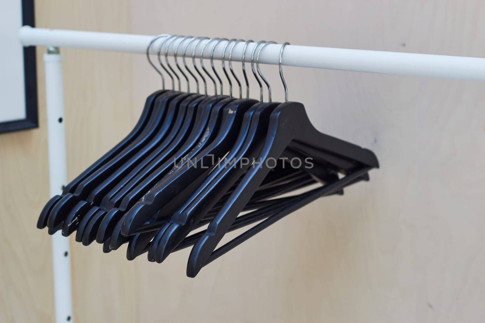 black wooden clothes hangers hang on a rail. by electrovenik