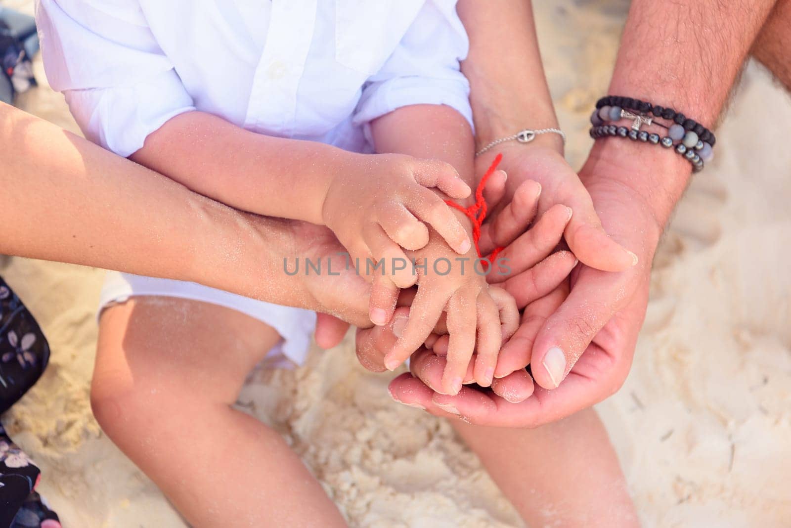 Hands of mom dad and little boy close-up on the beach by Kai_Grim