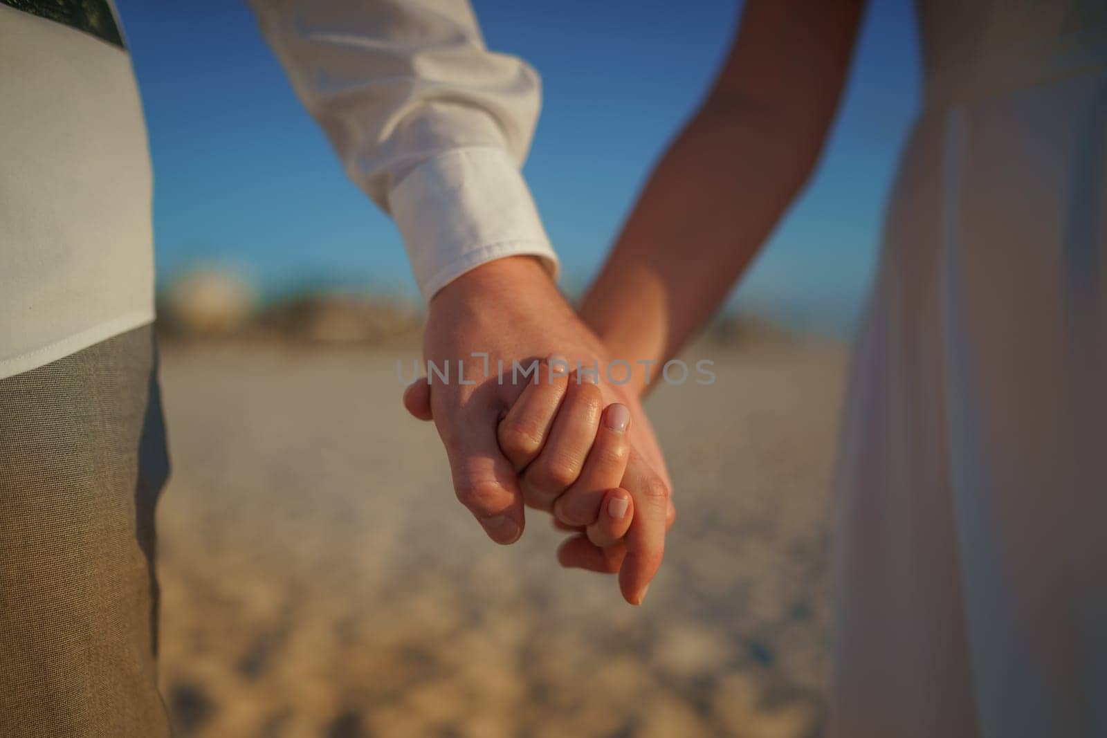 Man and woman, newlyweds holding hands with blurred background. by Kai_Grim