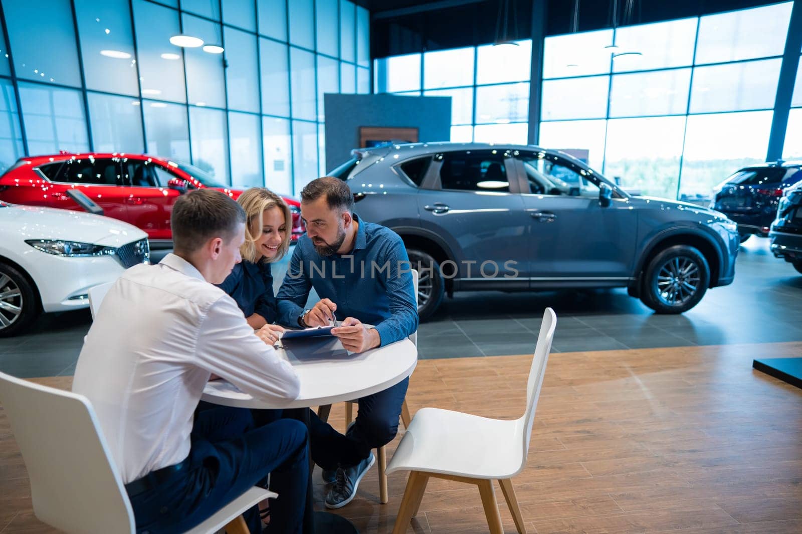 Happy caucasian couple signs a contract for the purchase of a car salon
