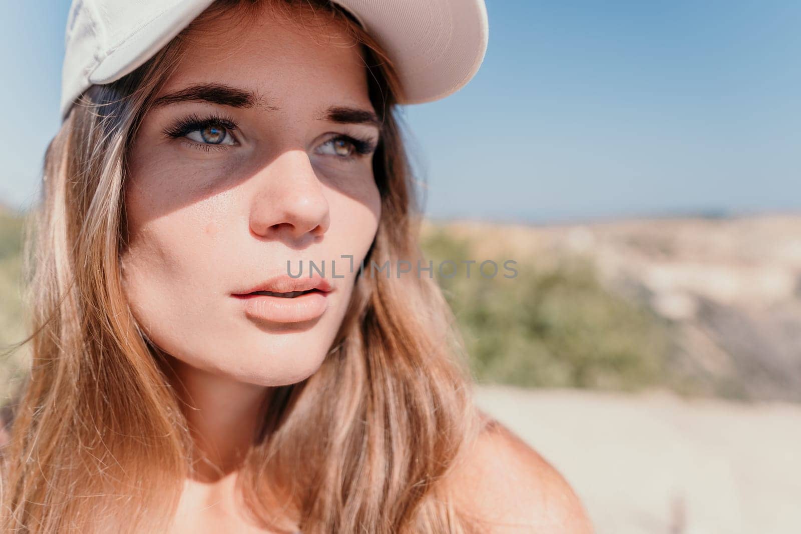 Side view a Young beautiful sensual woman in a mint long dress posing on a volcanic rock high above the sea during sunset. Girl on the nature on overcast sky background. Fashion photo