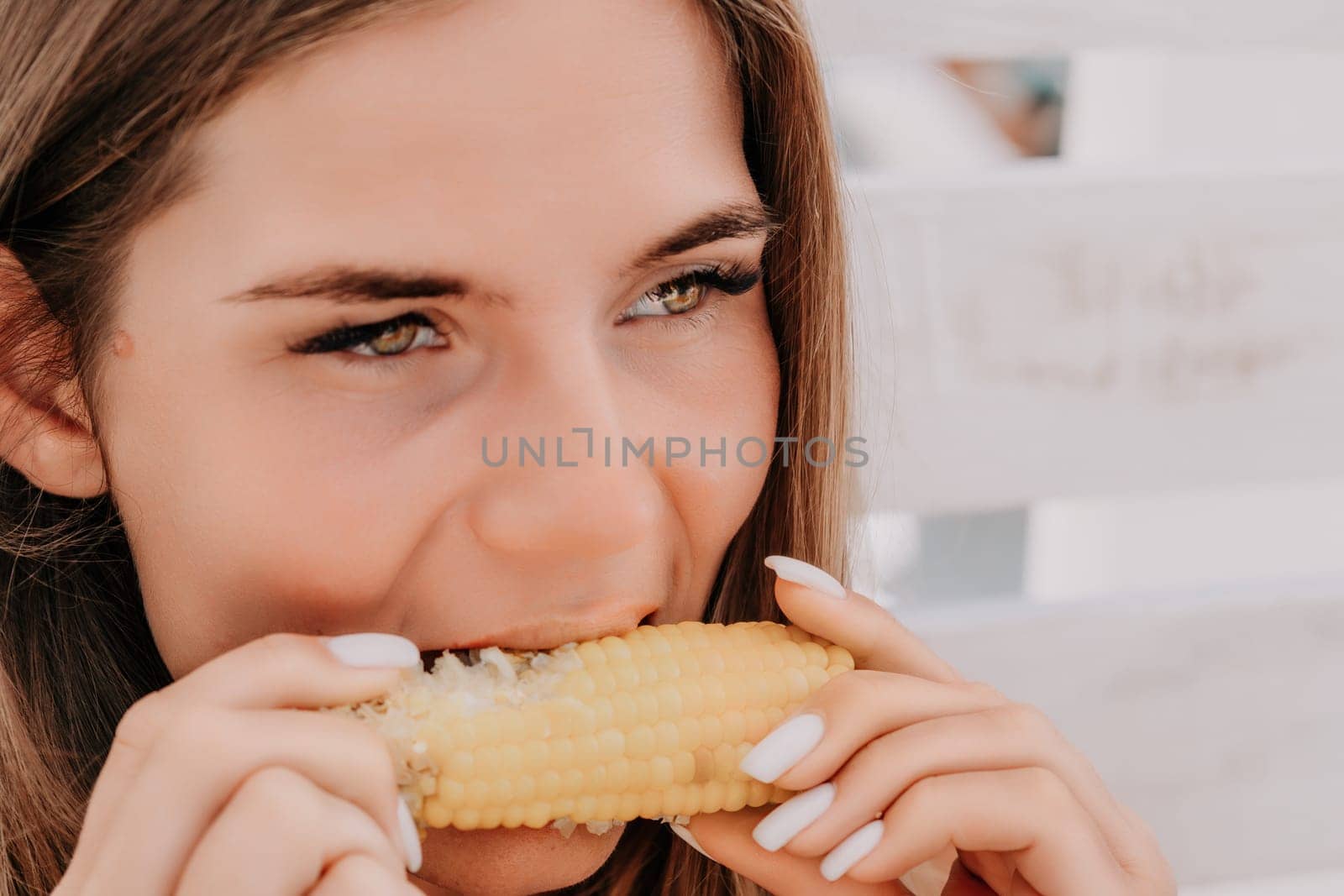 Healthy vegetarian hipster woman in summer outfit eat grilled corn and look to camera. Sexy lady on sea beach sunset or ocean sunrise. Travel, explore, active yoga and meditation lifestyle concept.