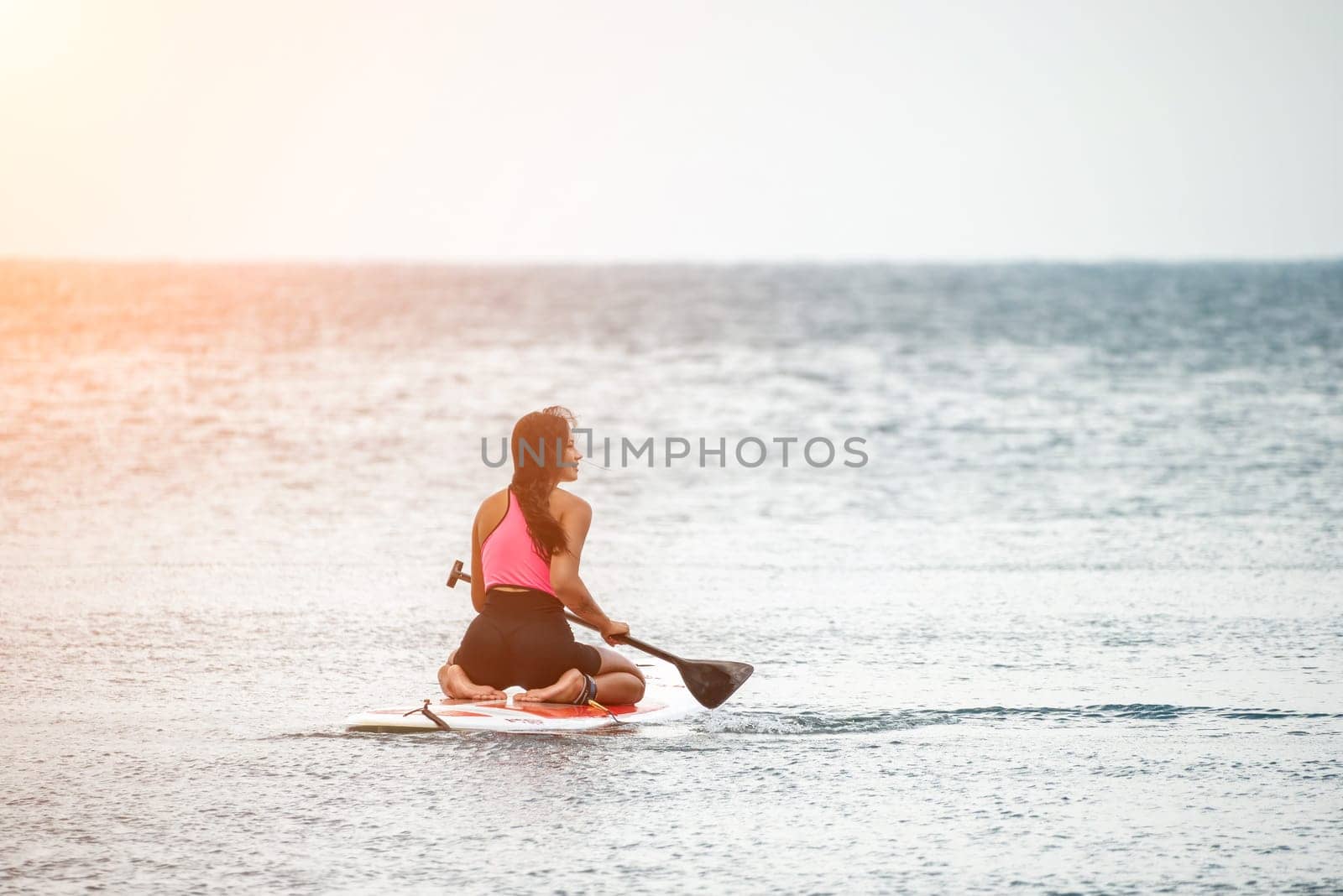 Sea woman and man on sup. Silhouette of happy young woman and man, surfing on SUP board, confident paddling through water surface. Idyllic sunset. Active lifestyle at sea or river