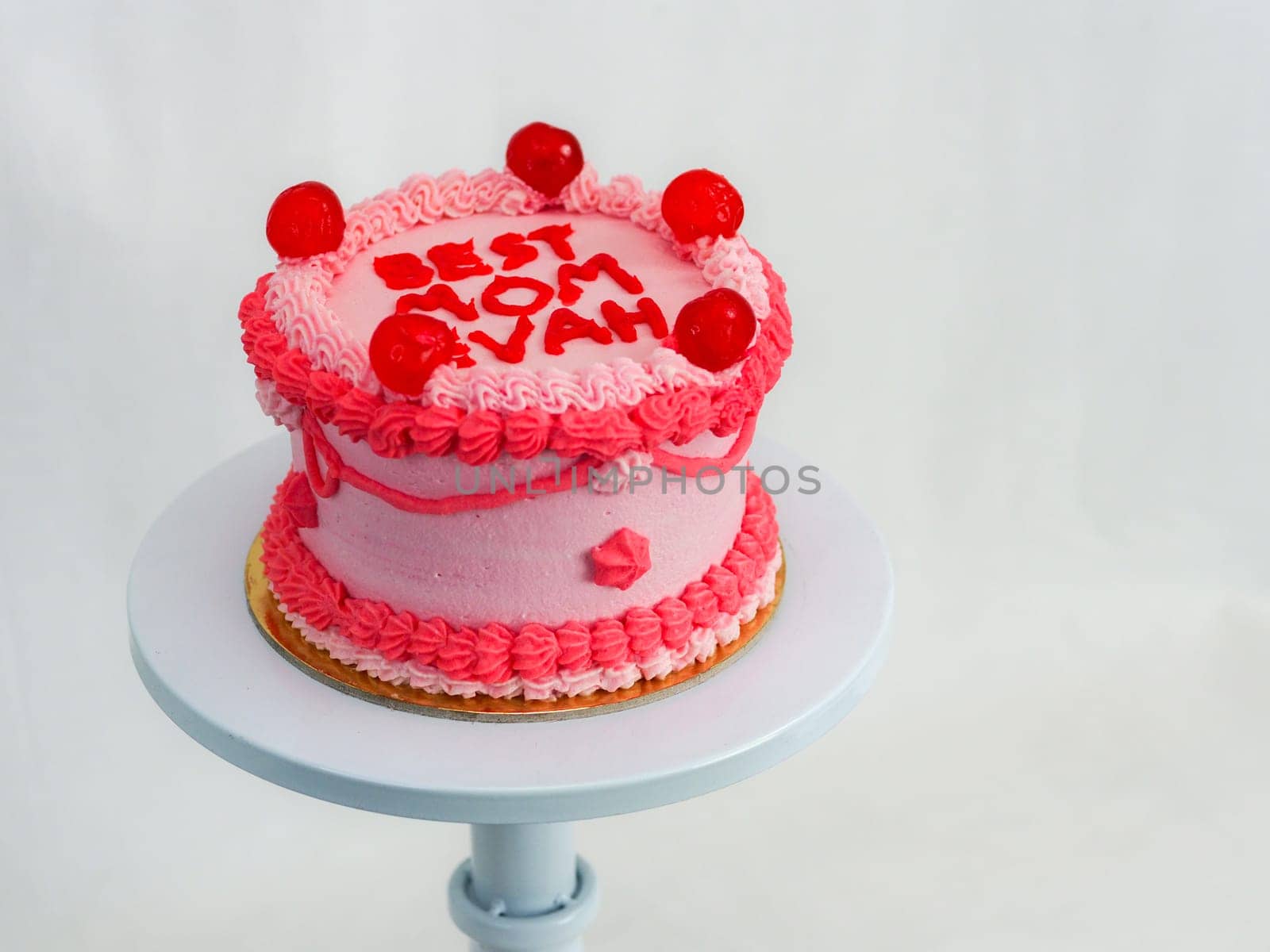 frosted pink red cake for mothers day celebration with funny text topping best mom evah on white studio background