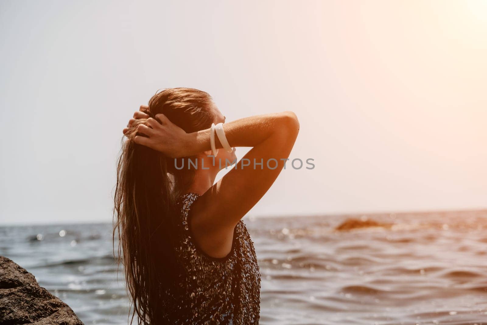 Woman travel sea. Young Happy woman in a long red dress posing on a beach near the sea on background of volcanic rocks, like in Iceland, sharing travel adventure journey