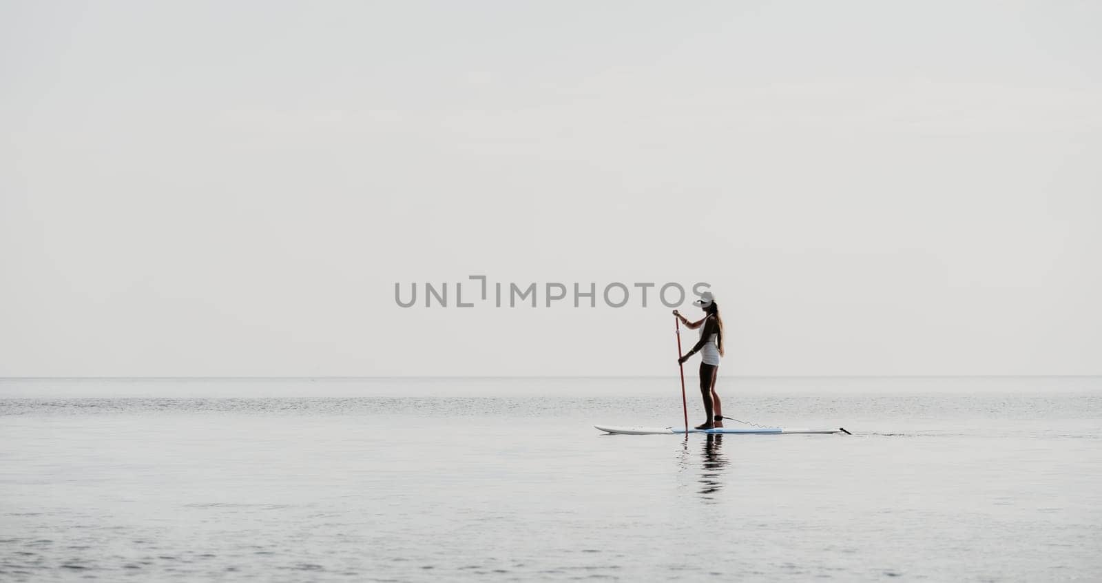 Close up shot of beautiful young caucasian woman with black hair and freckles looking at camera and smiling. Cute woman portrait in a pink bikini posing on a volcanic rock high above the sea