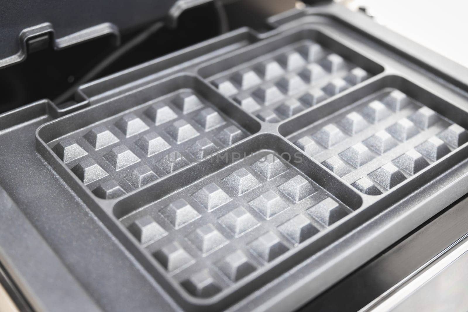 Close-up of a new 4-section electric waffle maker for home cooking.