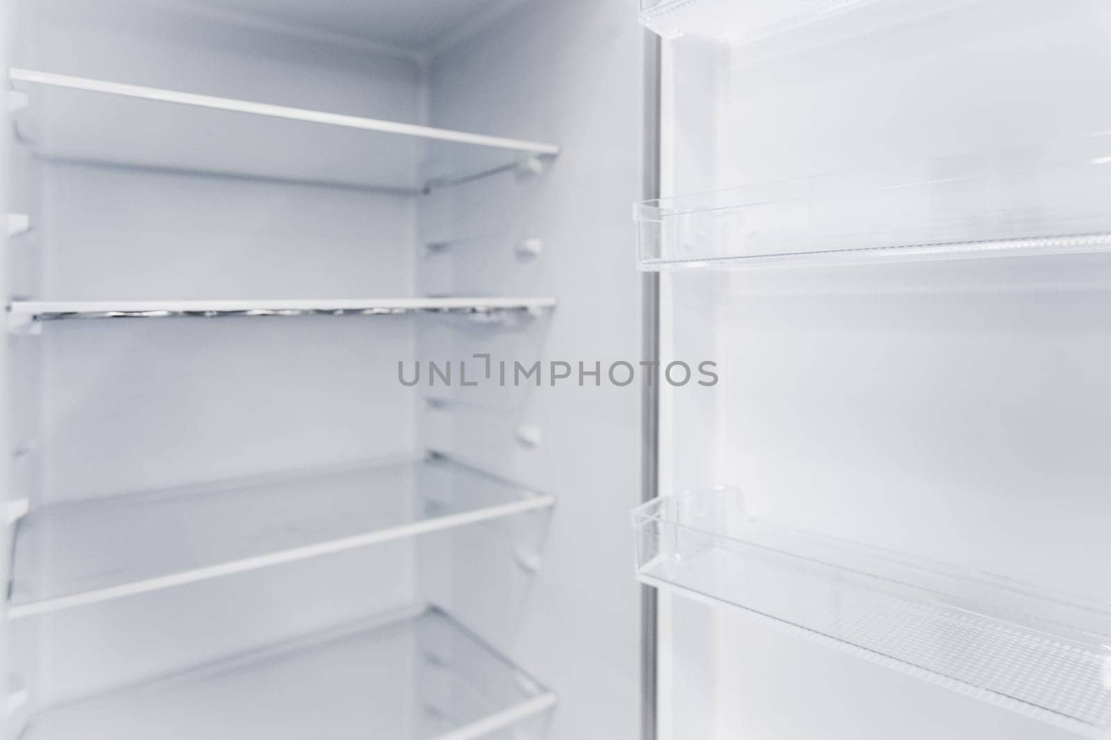 Empty white vertical new home refrigerator with shelves.