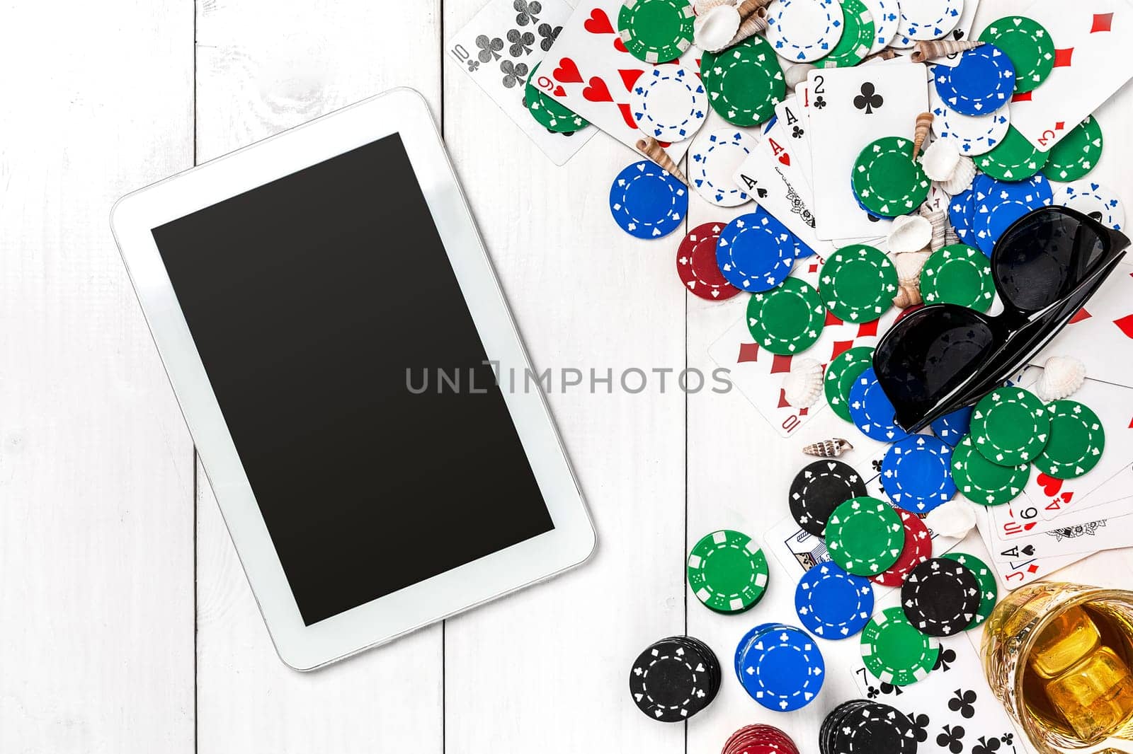 Gambling. Poker chips, cards and the dice nearby tablet on white wooden table. Top view. Copyspace. Poker. Summer