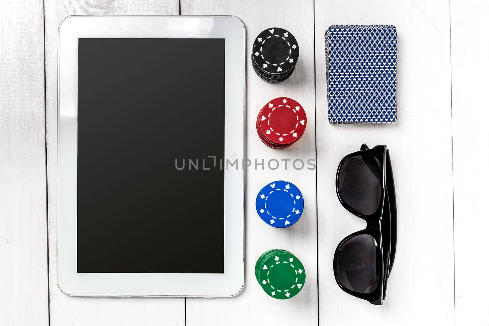 Gambling. Poker chips, cards and the dice nearby tablet on white wooden table. Top view. Copyspace. Poker. Summer