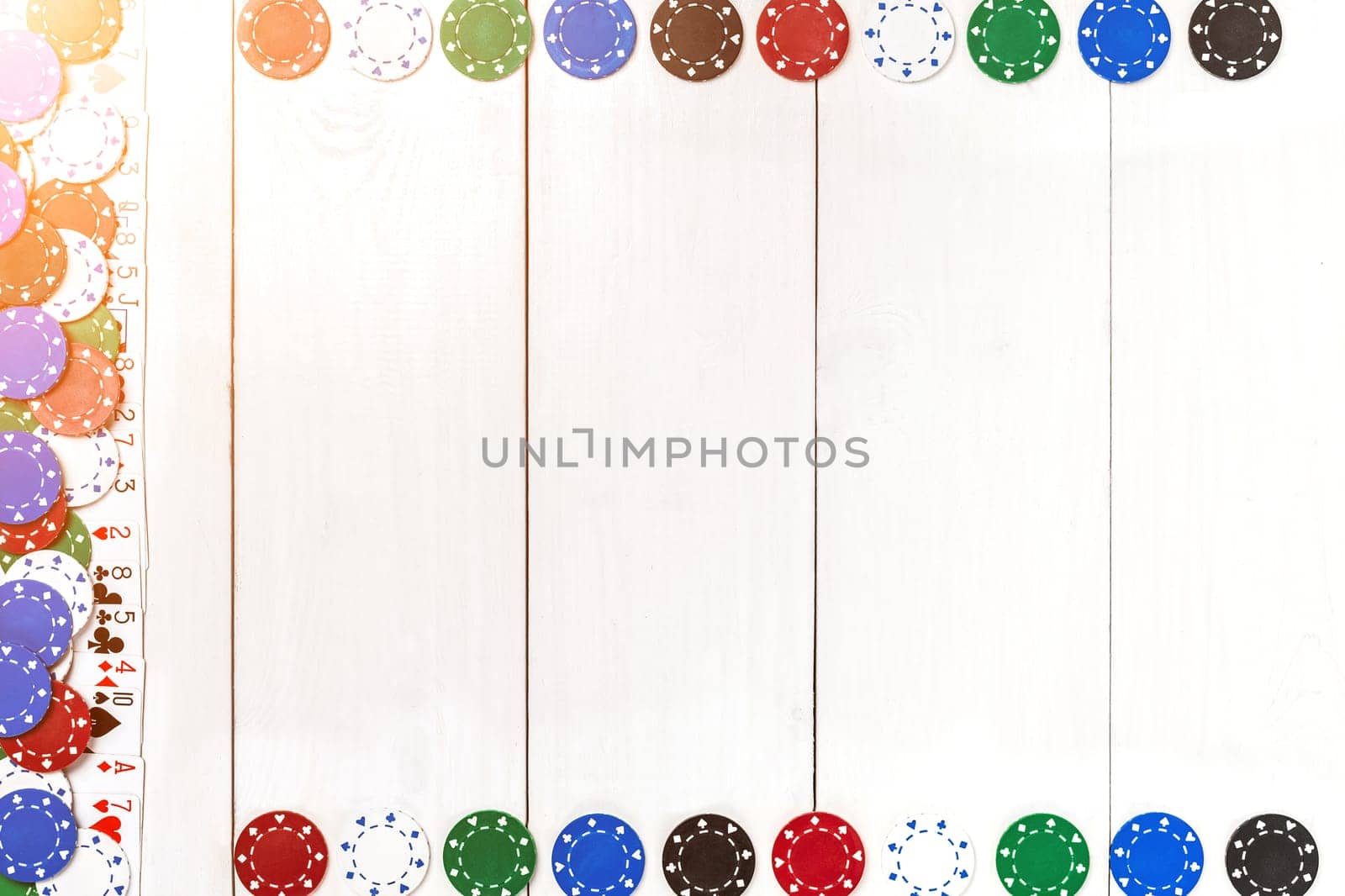 Playing cards and poker chips on white wooden background. Top view. Copyspace. Poker. Summer. Sun flare