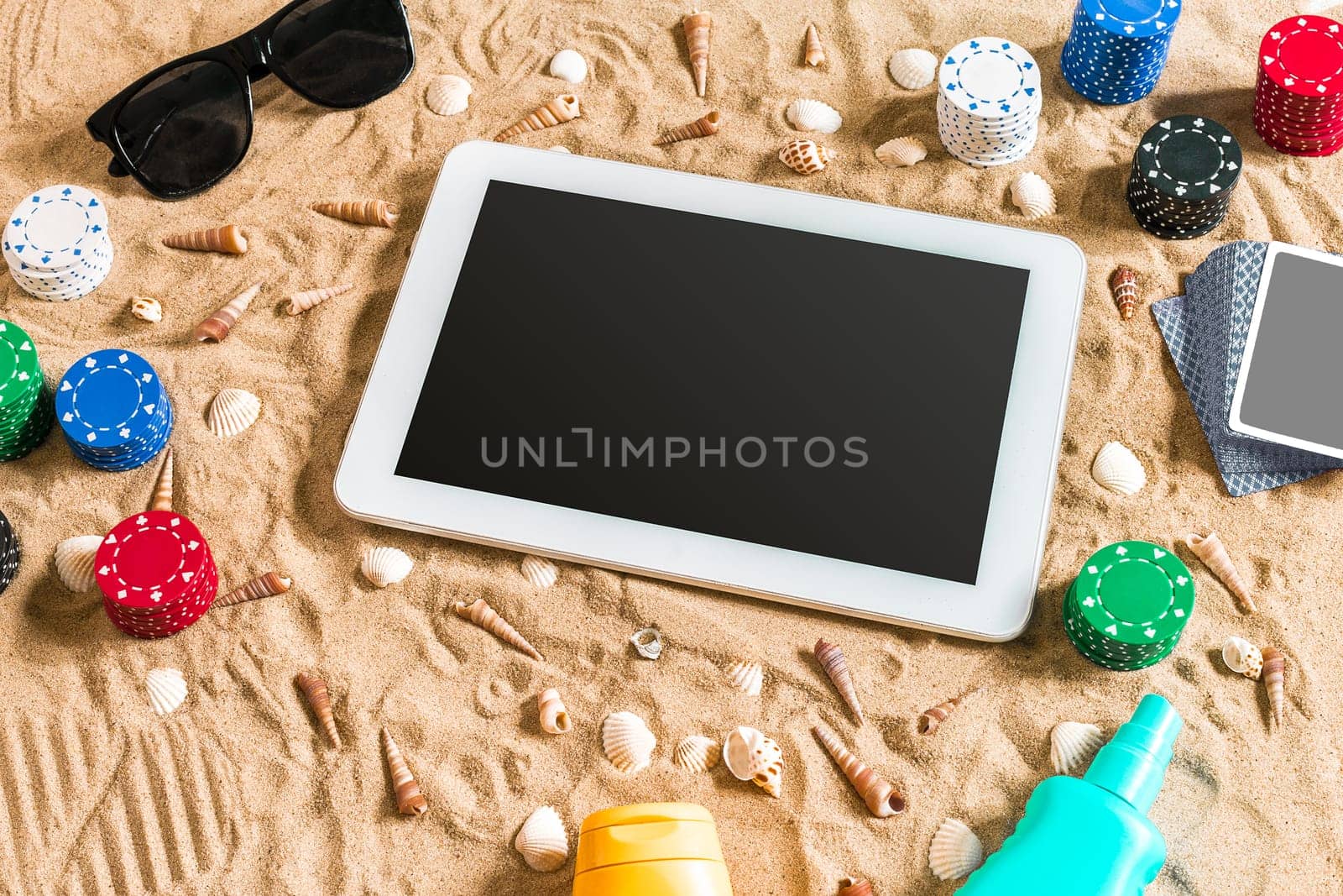Gambling on vacation concept - white sand with seashells , colored poker chips and cards. Top view. Copy space. Summer