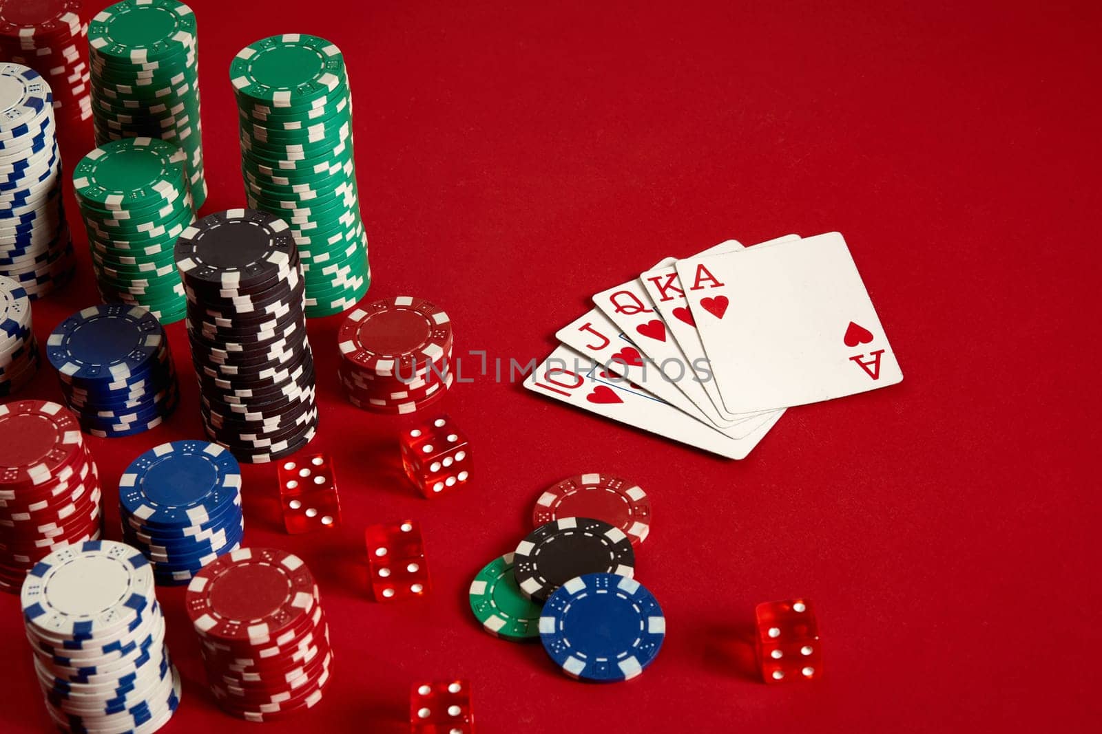 Casino gambling poker equipment and entertainment concept - close up of playing cards and chips at red background. Royal flush heart. Casino background. Copy space. Still life