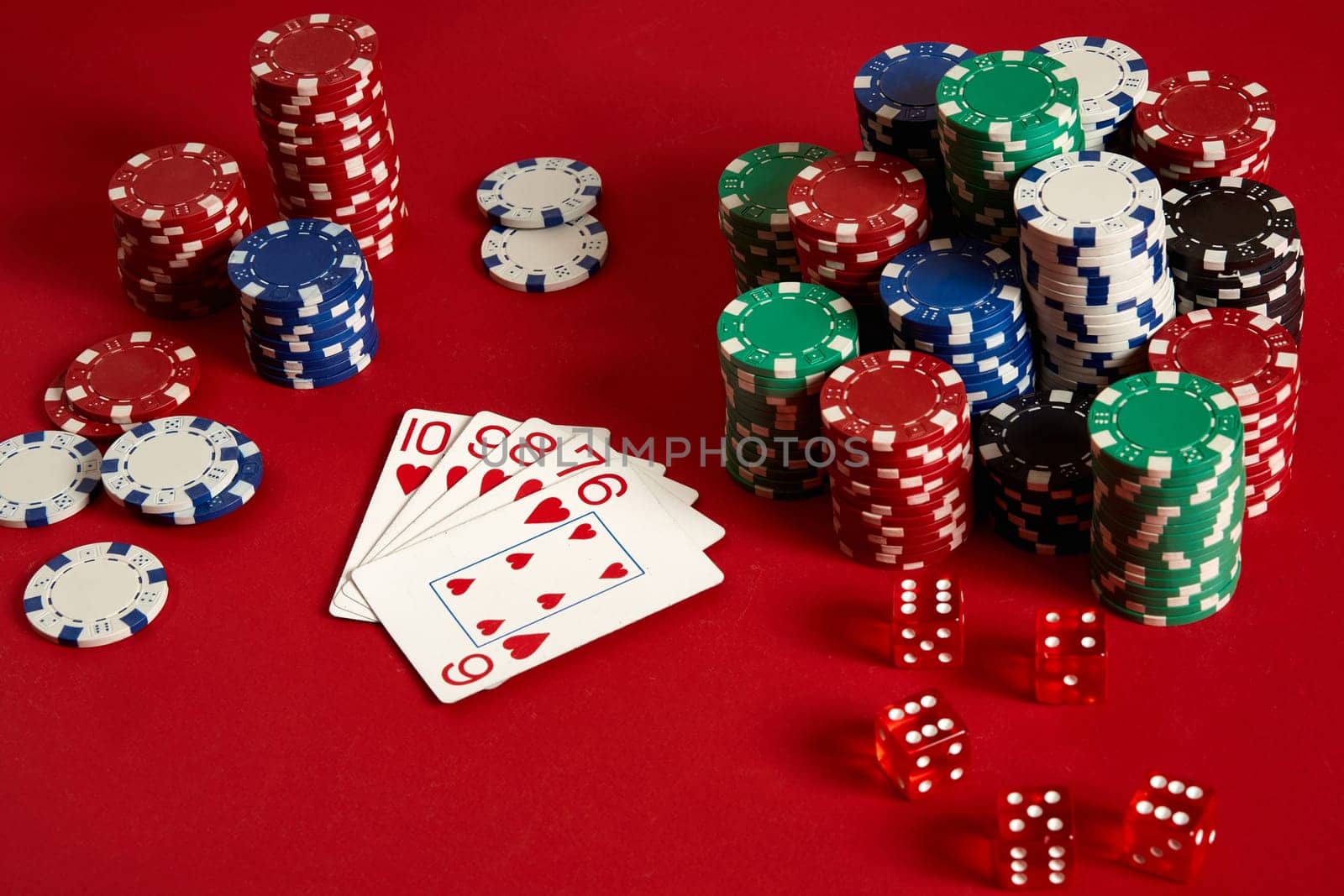 Casino gambling poker equipment and entertainment concept - close up of playing cards and chips at red background. Straight Flush. Casino background. Copy space. Still life