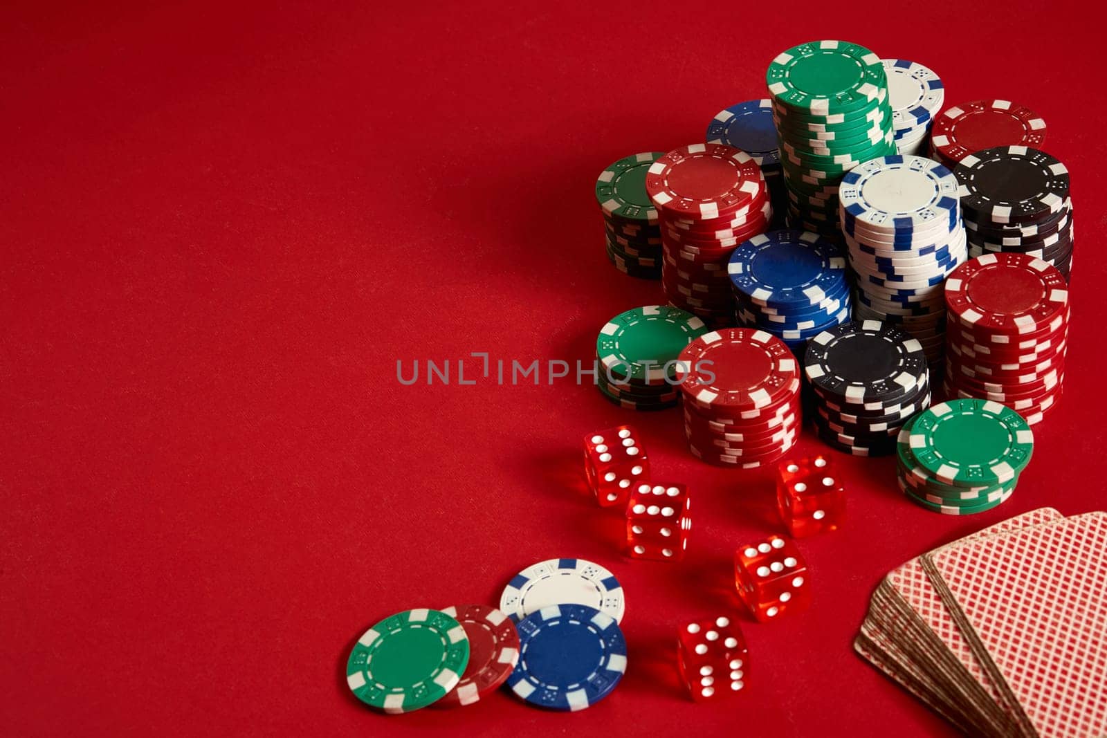 Poker chips and Card deck on red background. Group of different poker chips. Casino background. Copy space. Still life